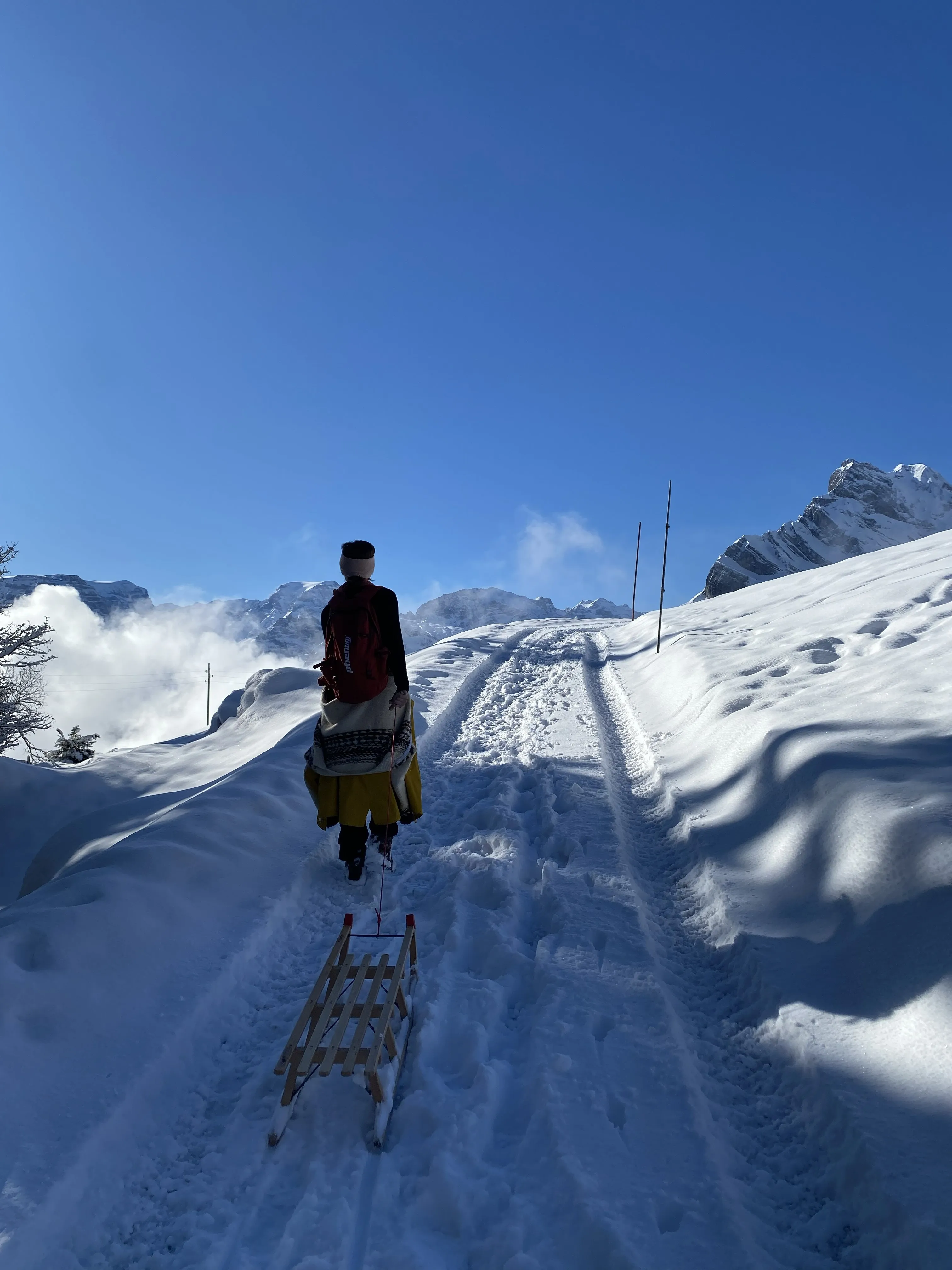 Climbing the snowy track with a sledge and backpack toward the Glarus peaks.