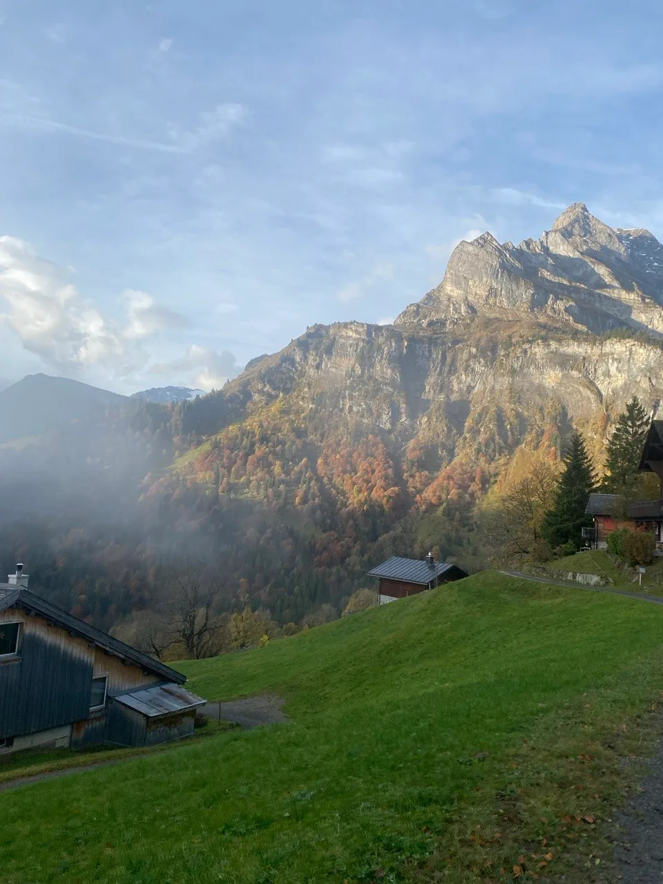 Autumn alpine hamlet with rugged rocky peaks rising through the mist.