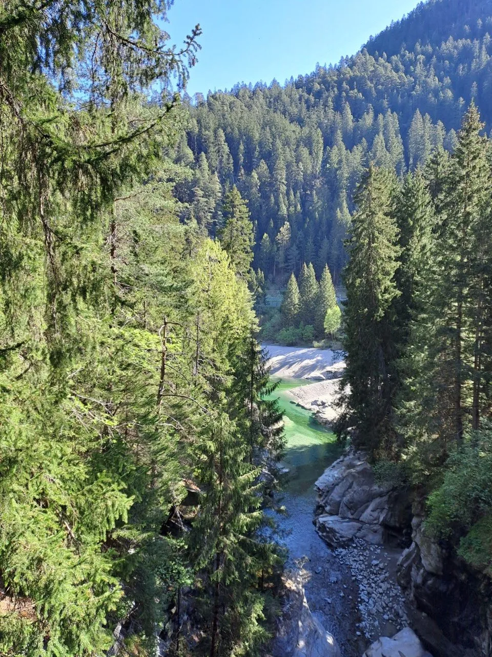 View down into the gorge with a turquoise pool and gravel bank.