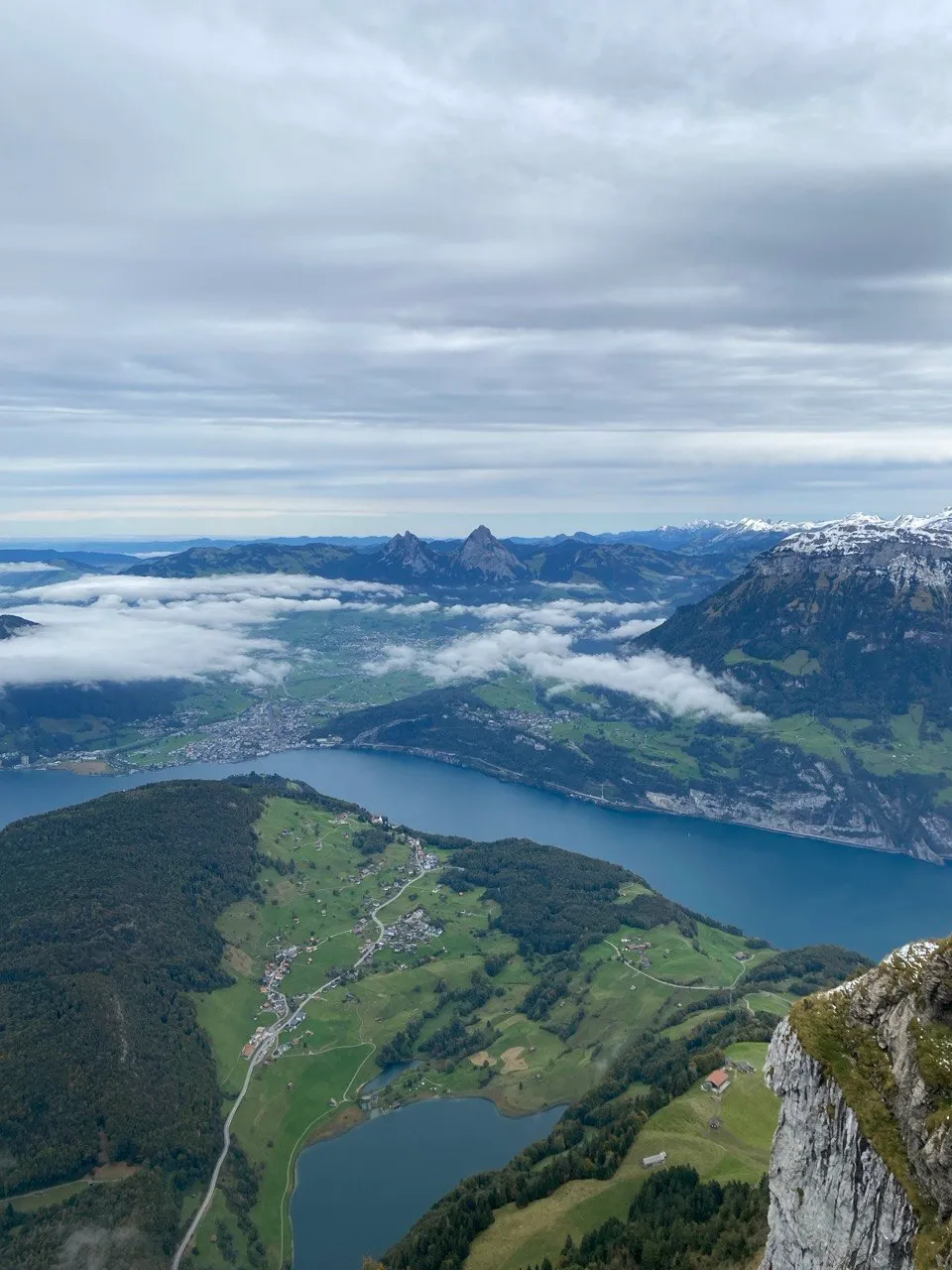 Aerial view over Lake Lucerne with drifting fog and mountain peaks.