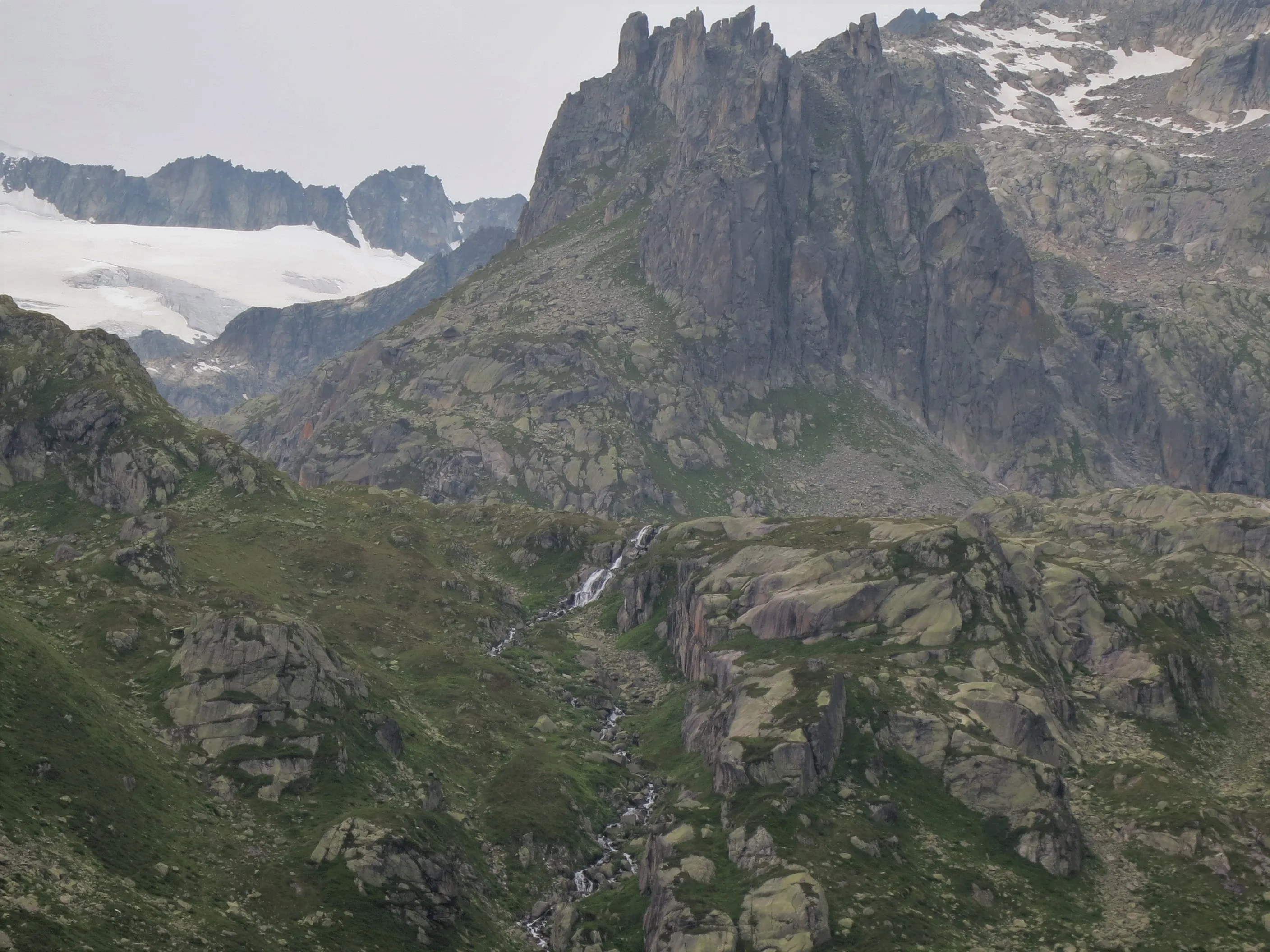 Granite towers and a waterfall in the Sidelen area above the Sidelen hut, with remnants of the Tiefen glacier near the Furka pass.