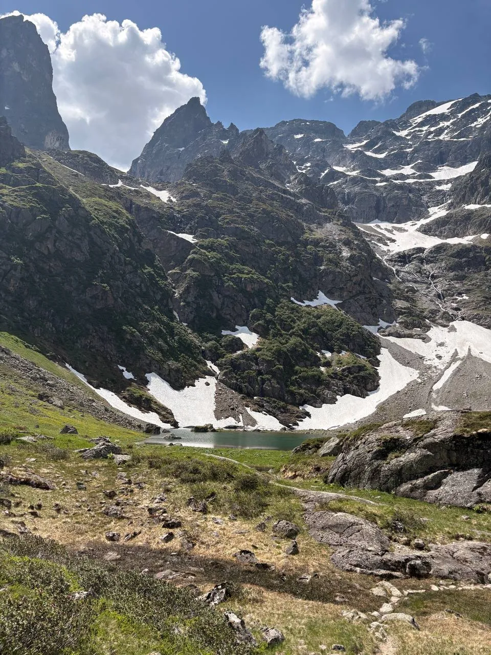 A small turquoise alpine lake in a green basin below the jagged Spannort towers.