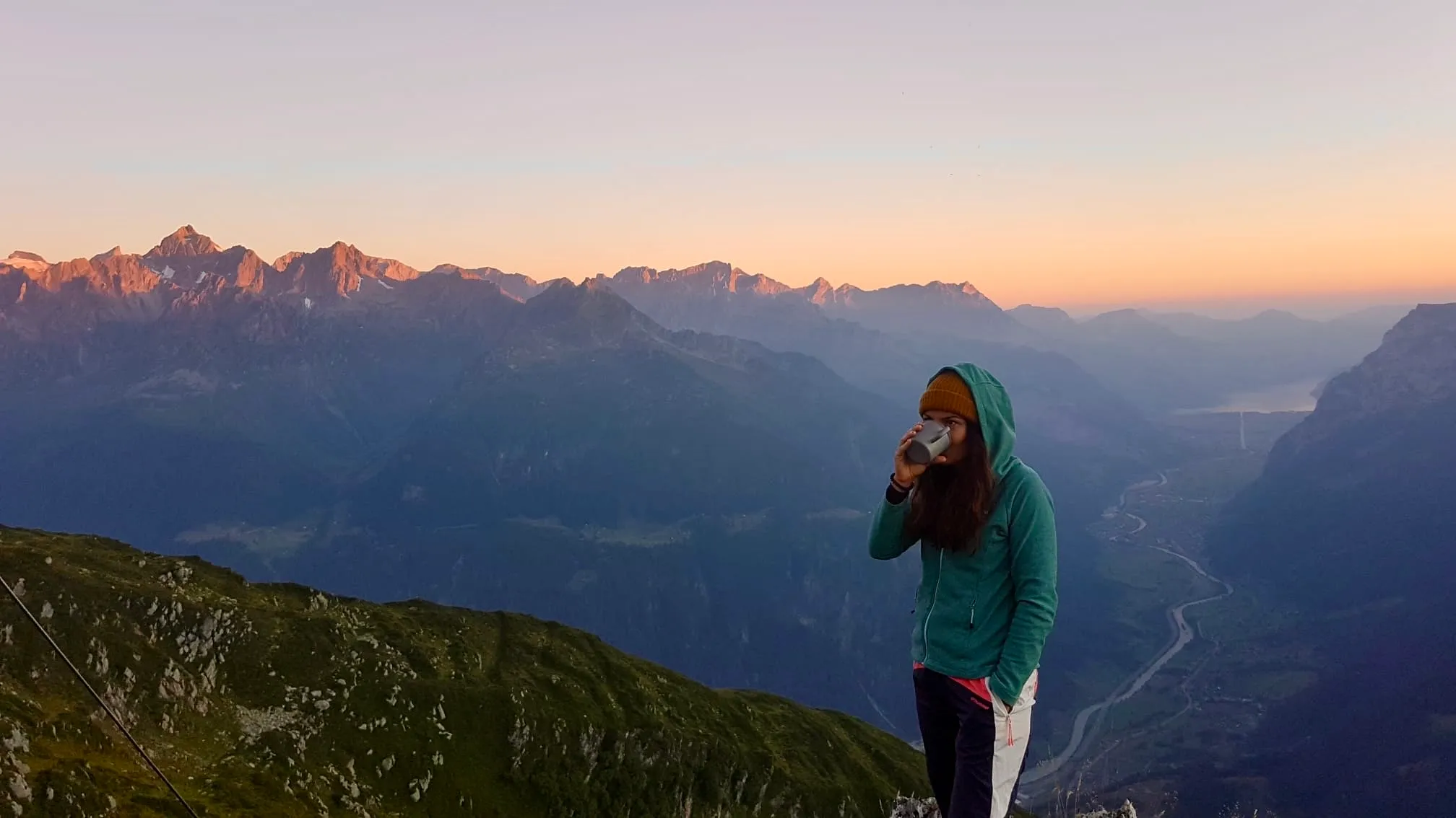 Warming up with a cup at dawn on the ridge, alpenglow lighting the opposite peaks.