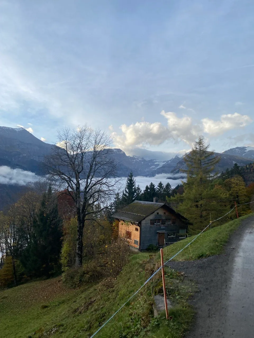 Mountain chalet at dusk with fog in the valley and snow-capped peaks.
