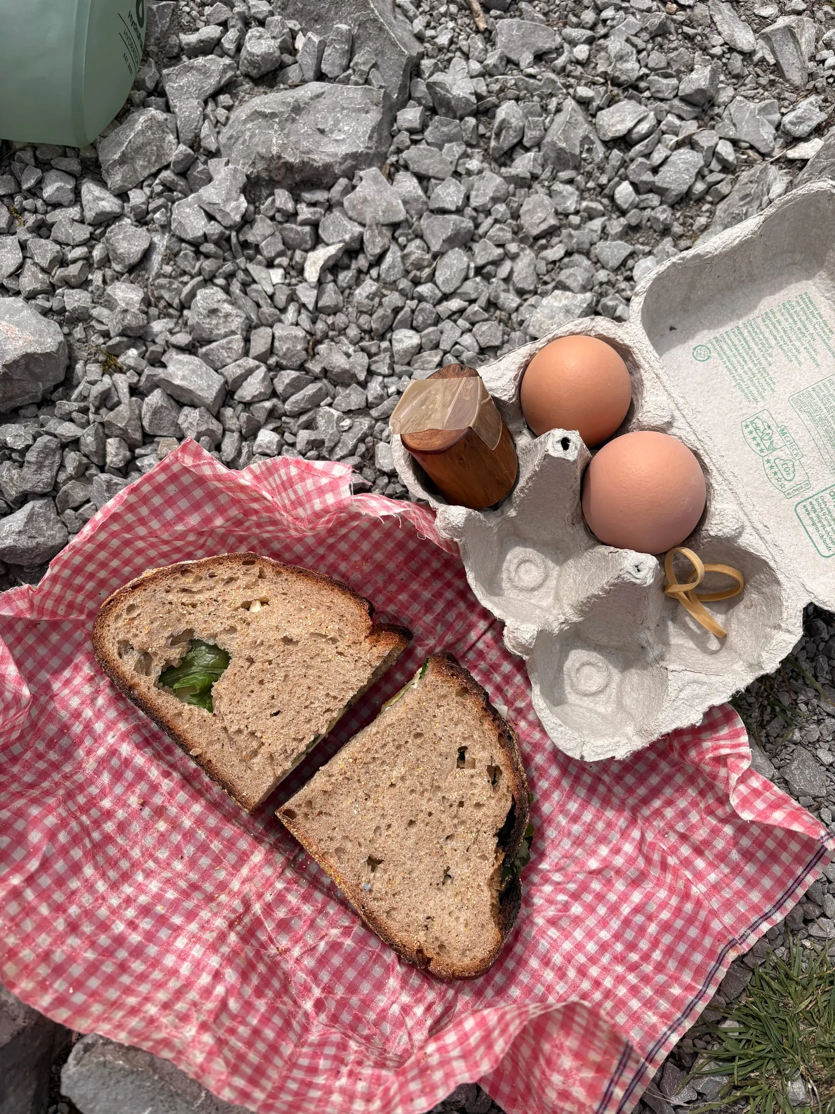 A picnic break on scree: hard-boiled eggs in a carton and bread on a red-checked cloth.