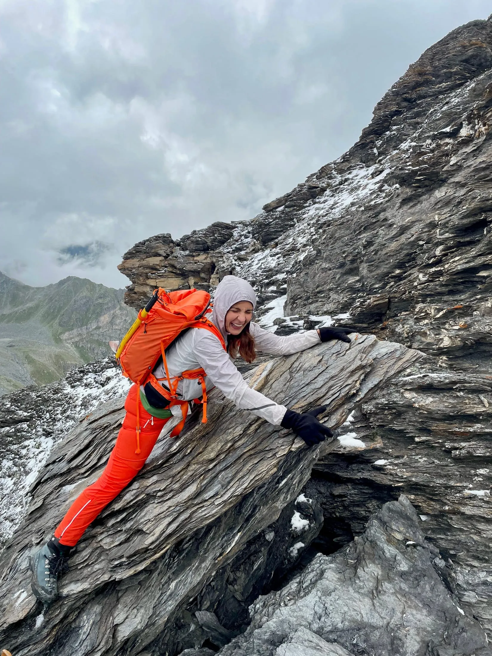 A hiker scrambling over grippy slabs on the rocky final section.