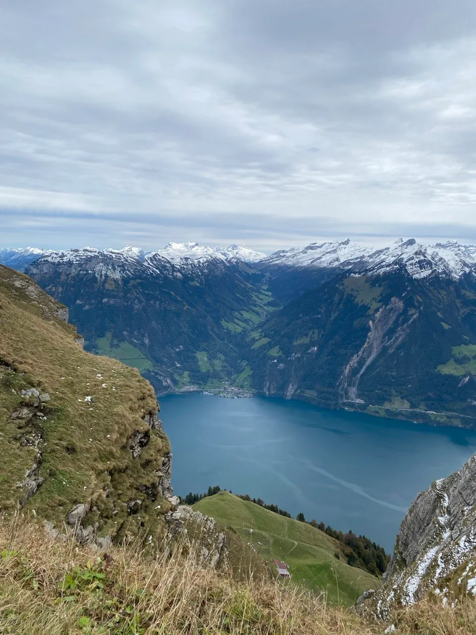 Deep blue alpine lake framed by snow-dusted peaks and green slopes.