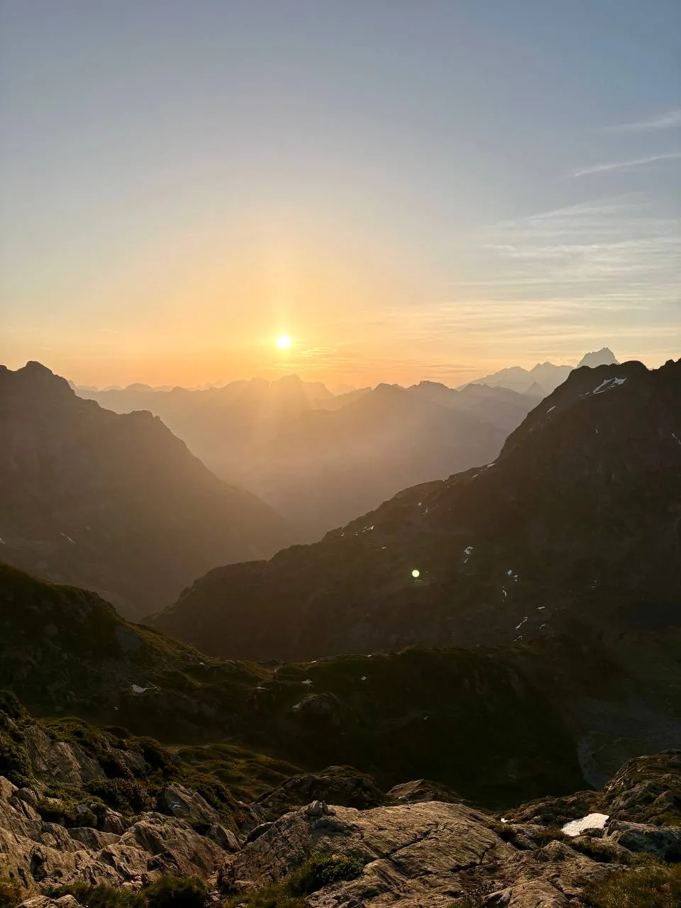 The sun rising over layered mountain ridges in golden light from high on the route.