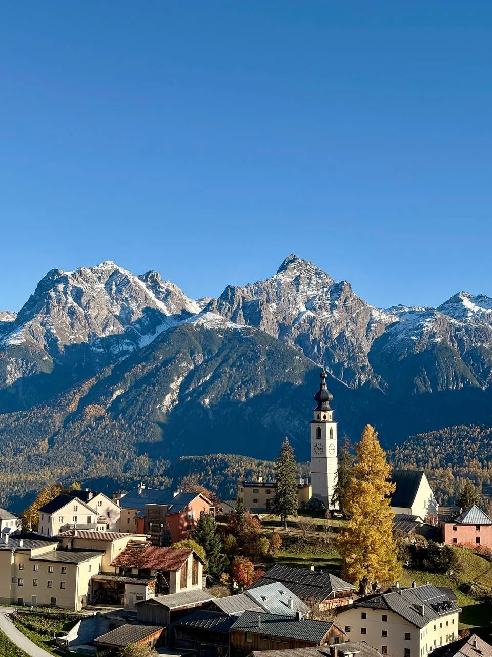 The Grisons village of Guarda with its white church tower, the sharp rocky summits of Piz Lischana behind.