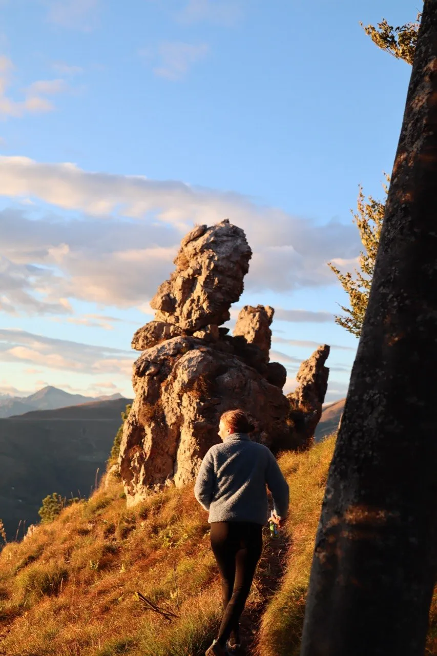 Hiker approaching the jagged rock towers of Denti della Vecchia along a ridge trail.