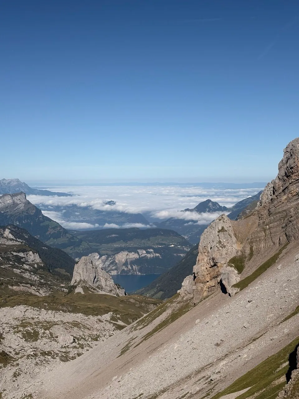 A deep-set lake beneath a sea of clouds, framed by grey rock walls.