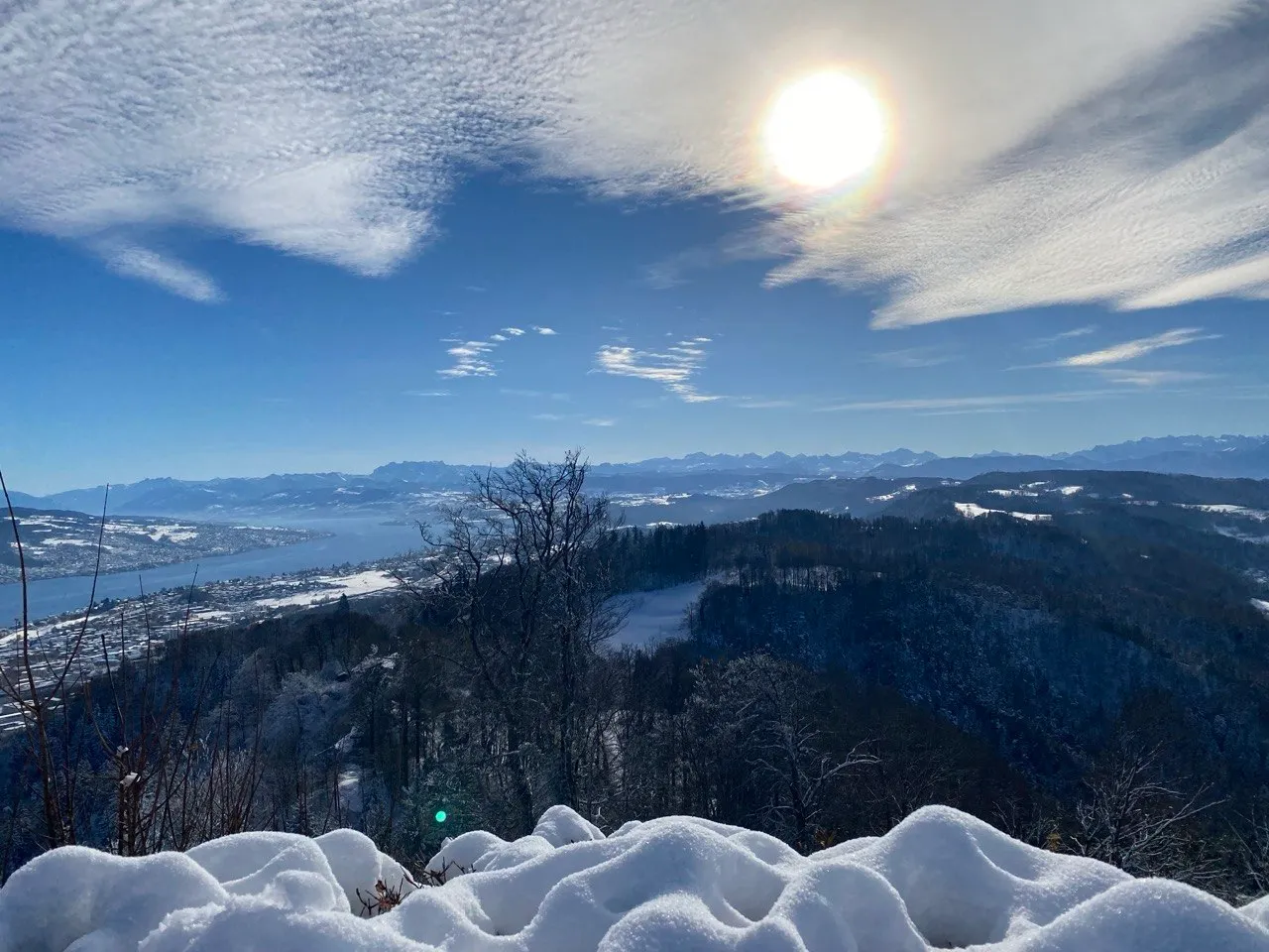 Sun over a wintery panorama with Lake Zurich and the Alps.