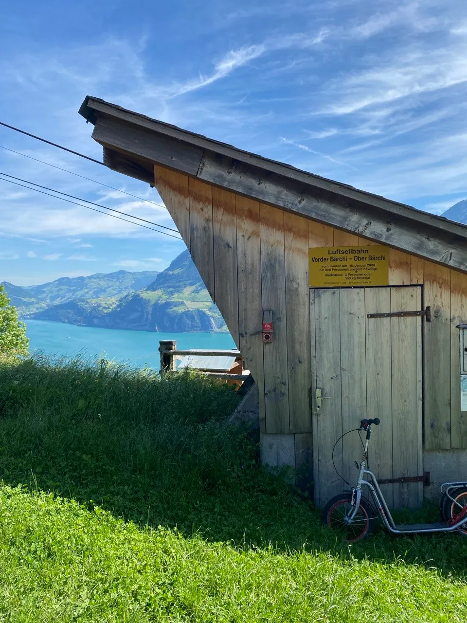 Cable car station hut perched above Lake Uri with kick-scooters leaning against it.