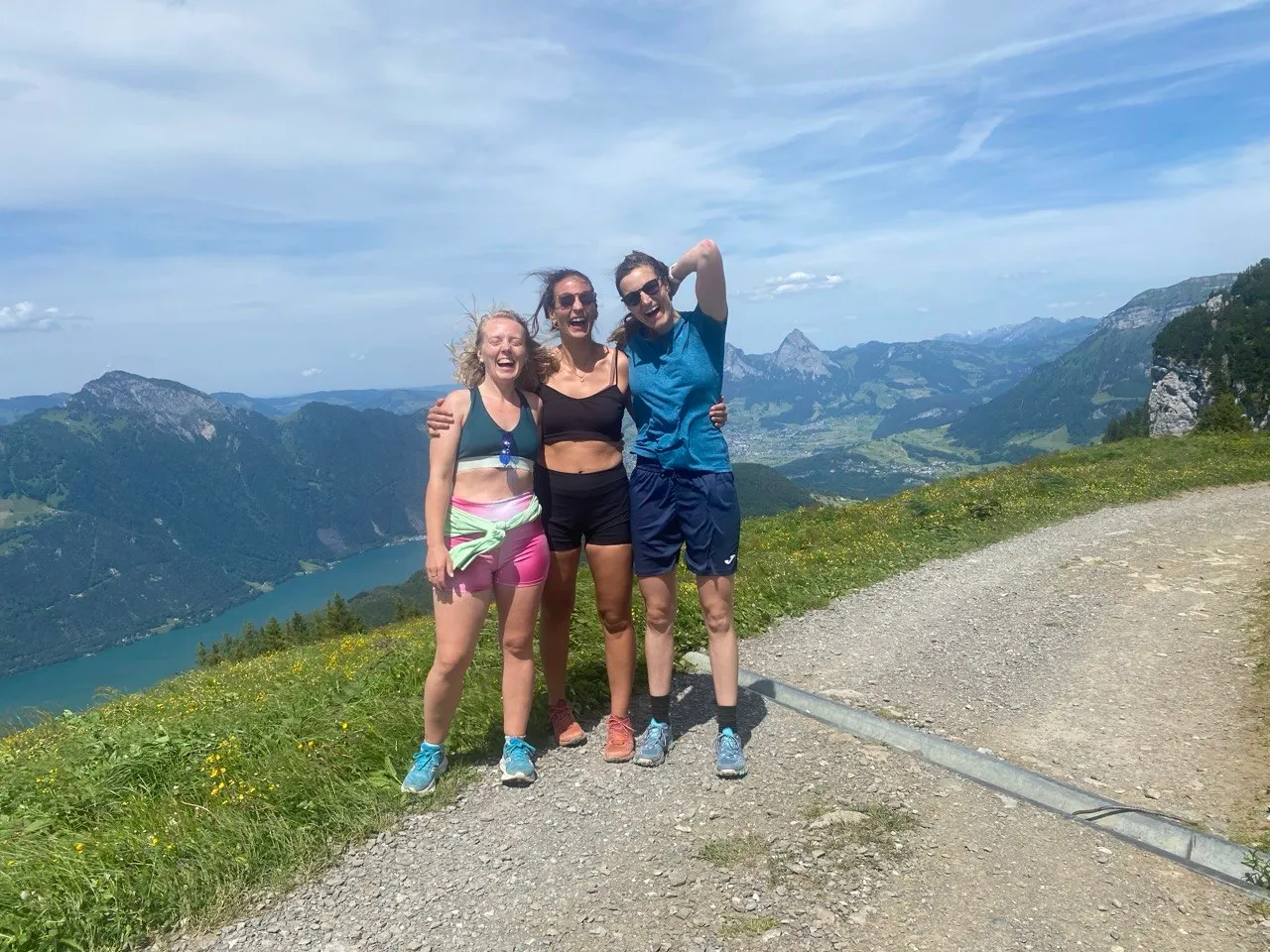Three hikers celebrating on the summit trail with the lake far below.