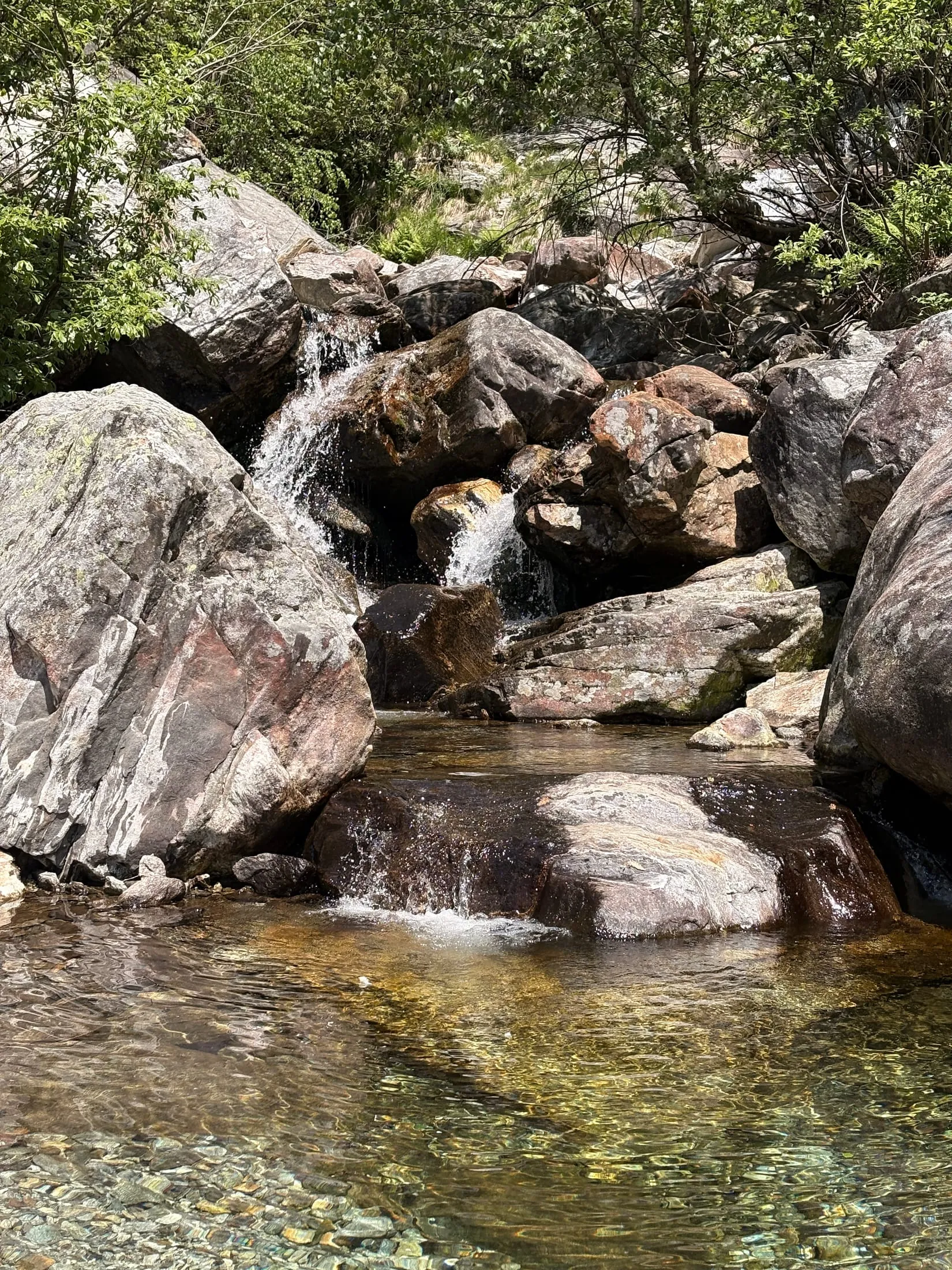 A clear mountain river cascading through boulders into turquoise pools.