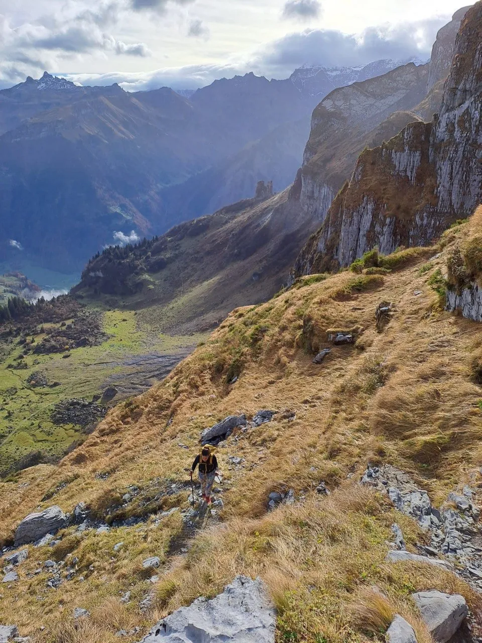 Hiker climbing a steep slope beside a dramatic gorge.
