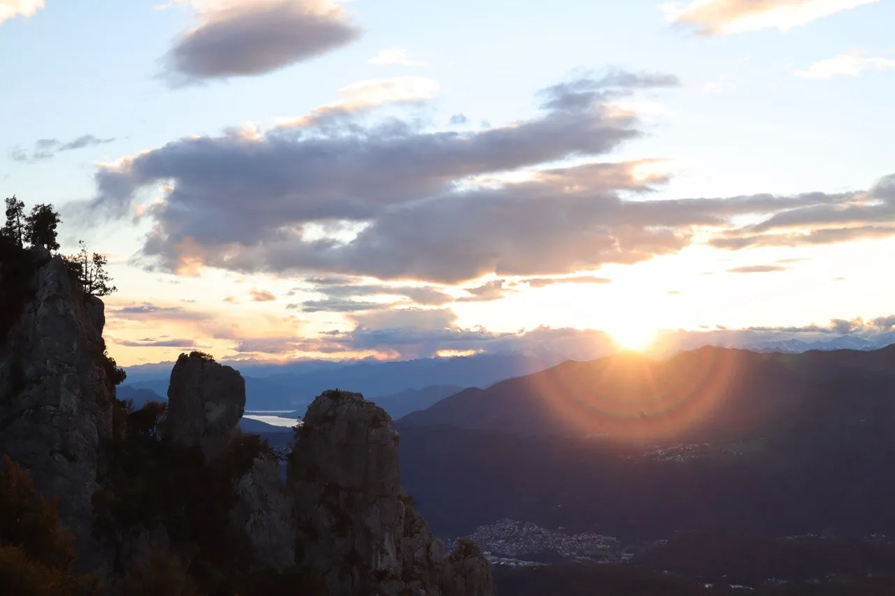 Sunset over the mountains with rock pinnacles in silhouette and a lake in the distance.