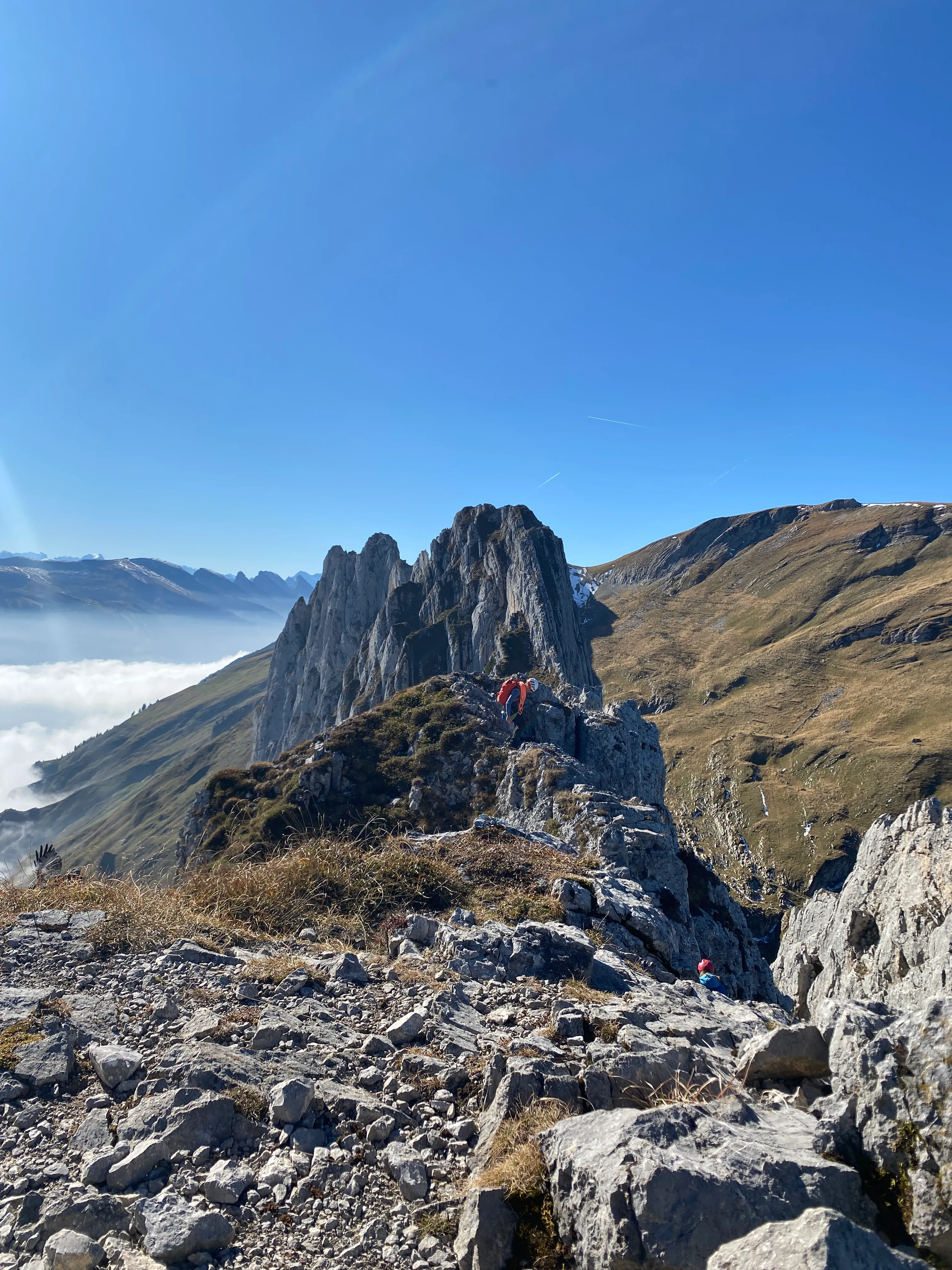 Hikers on the narrow rock ridge below the Kreuzberge, a sea of fog far below.