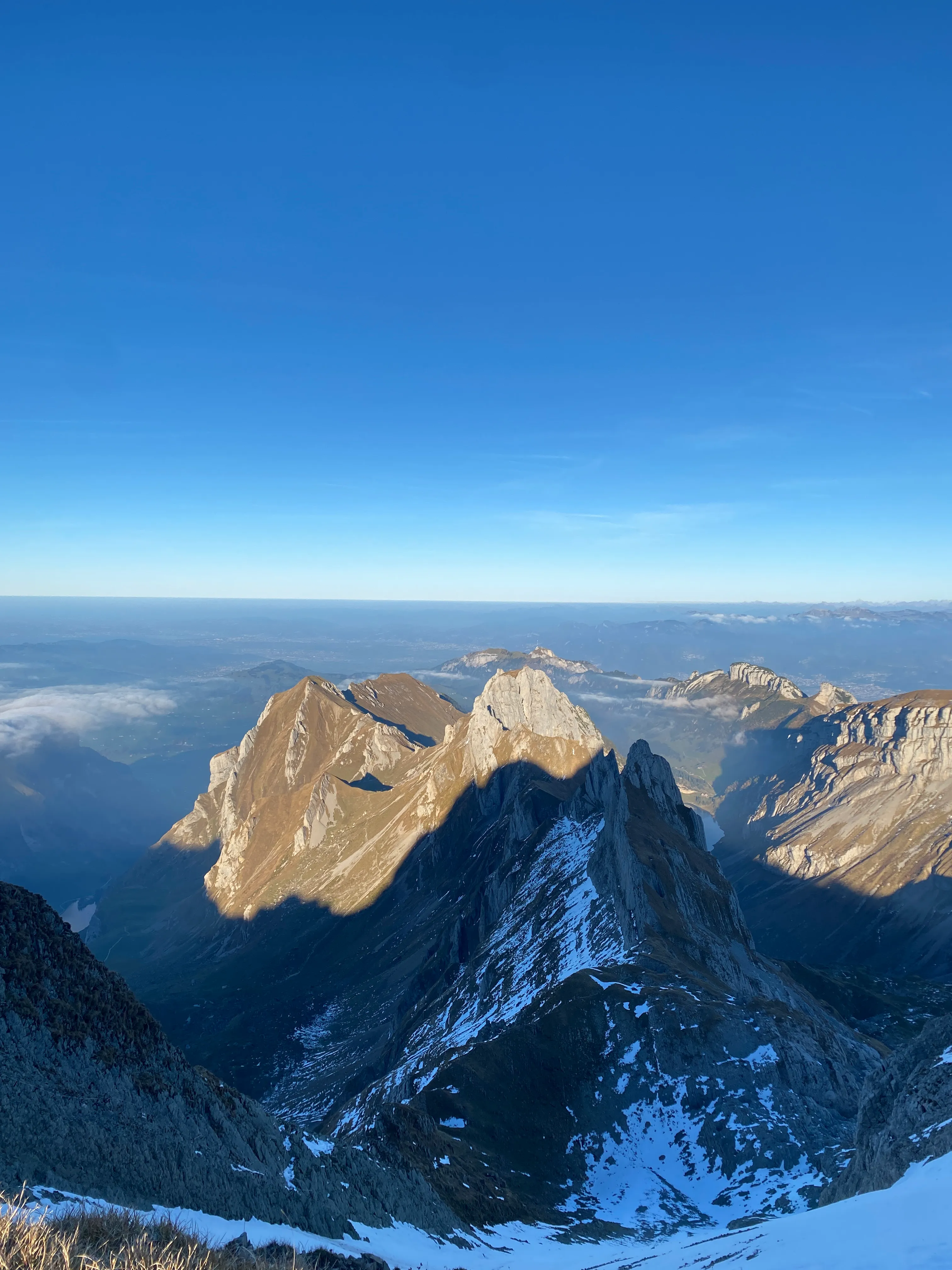 View over the Alpstein peaks in golden evening light, snow still in the shaded gullies.