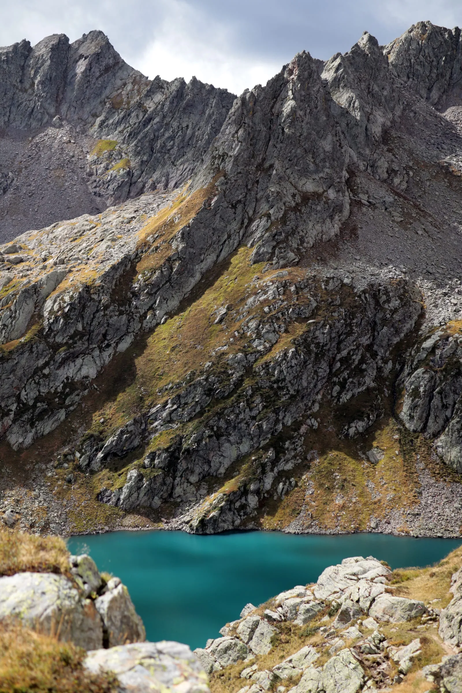 Brilliant turquoise mountain lake tucked between steep, jagged rock walls.