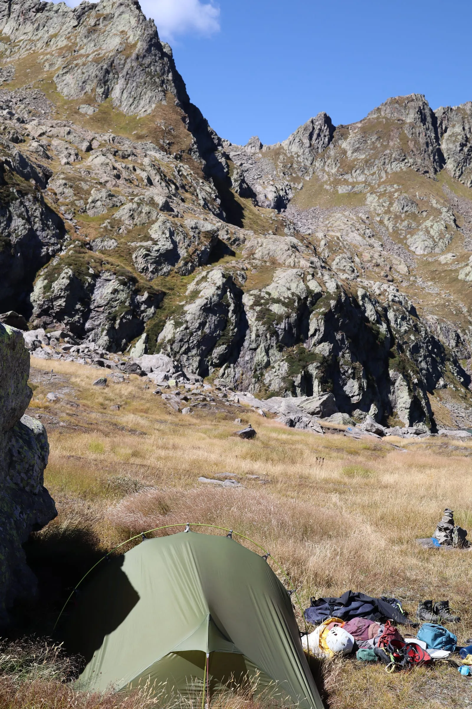 Bivouac with a green tent at the edge of a high plateau looking out over wild ridges.