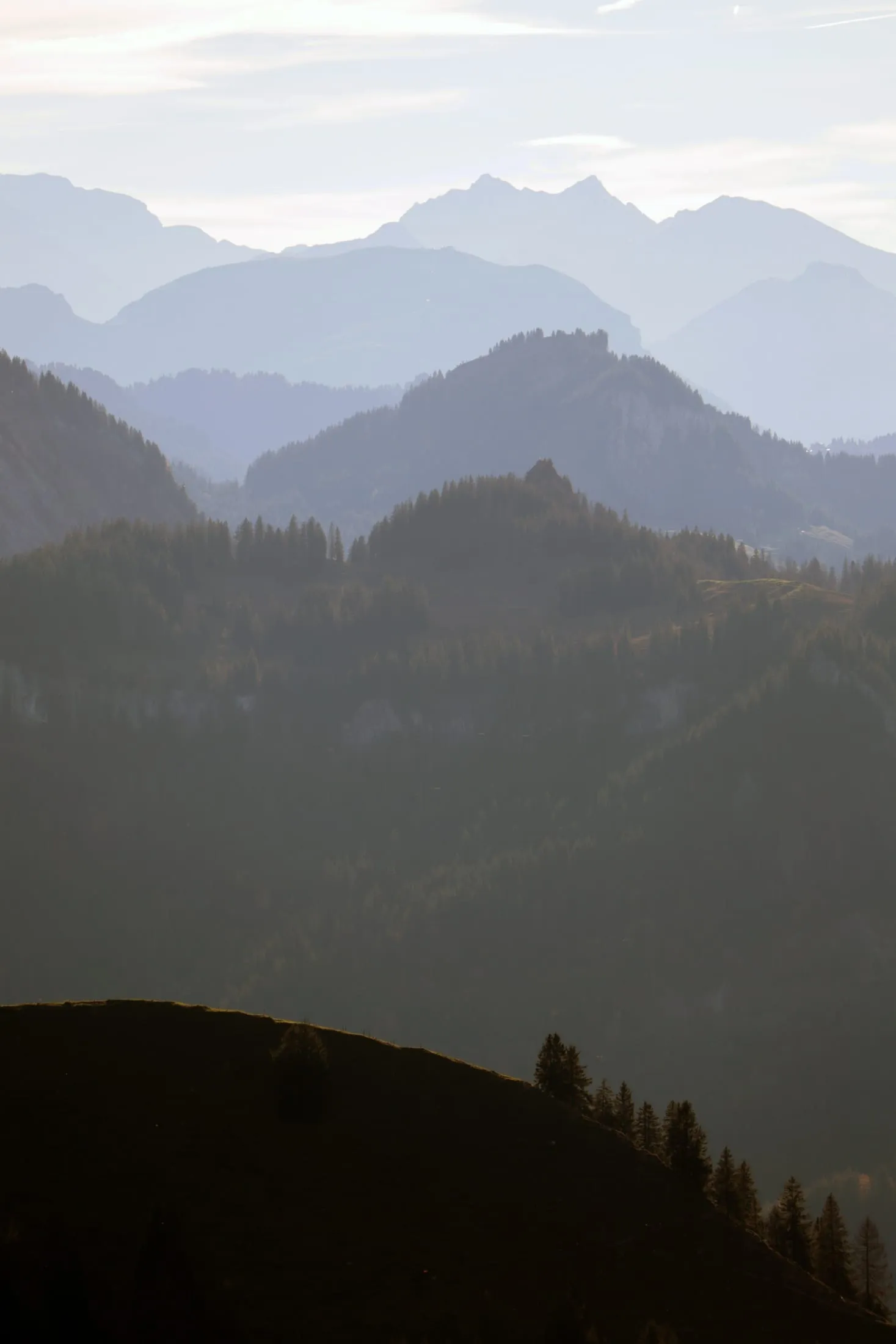 Layers of mountain silhouettes fading into hazy evening light.