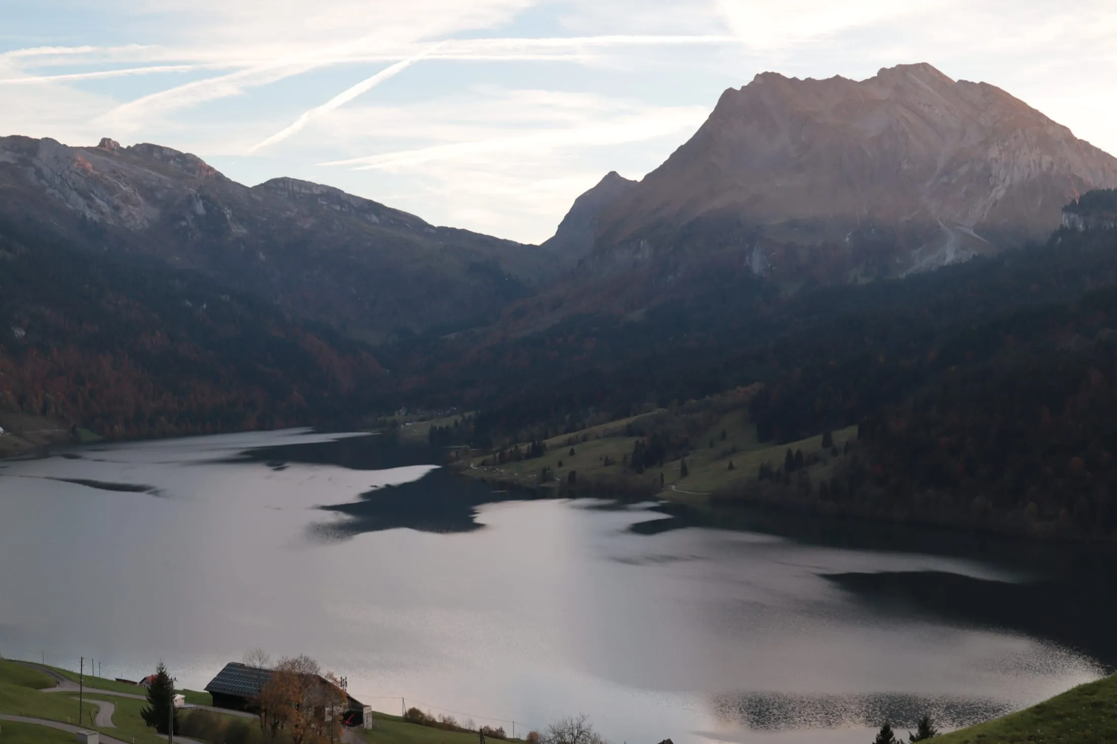 Evening mood over Lake Wägital with mountain backdrop and wispy clouds.