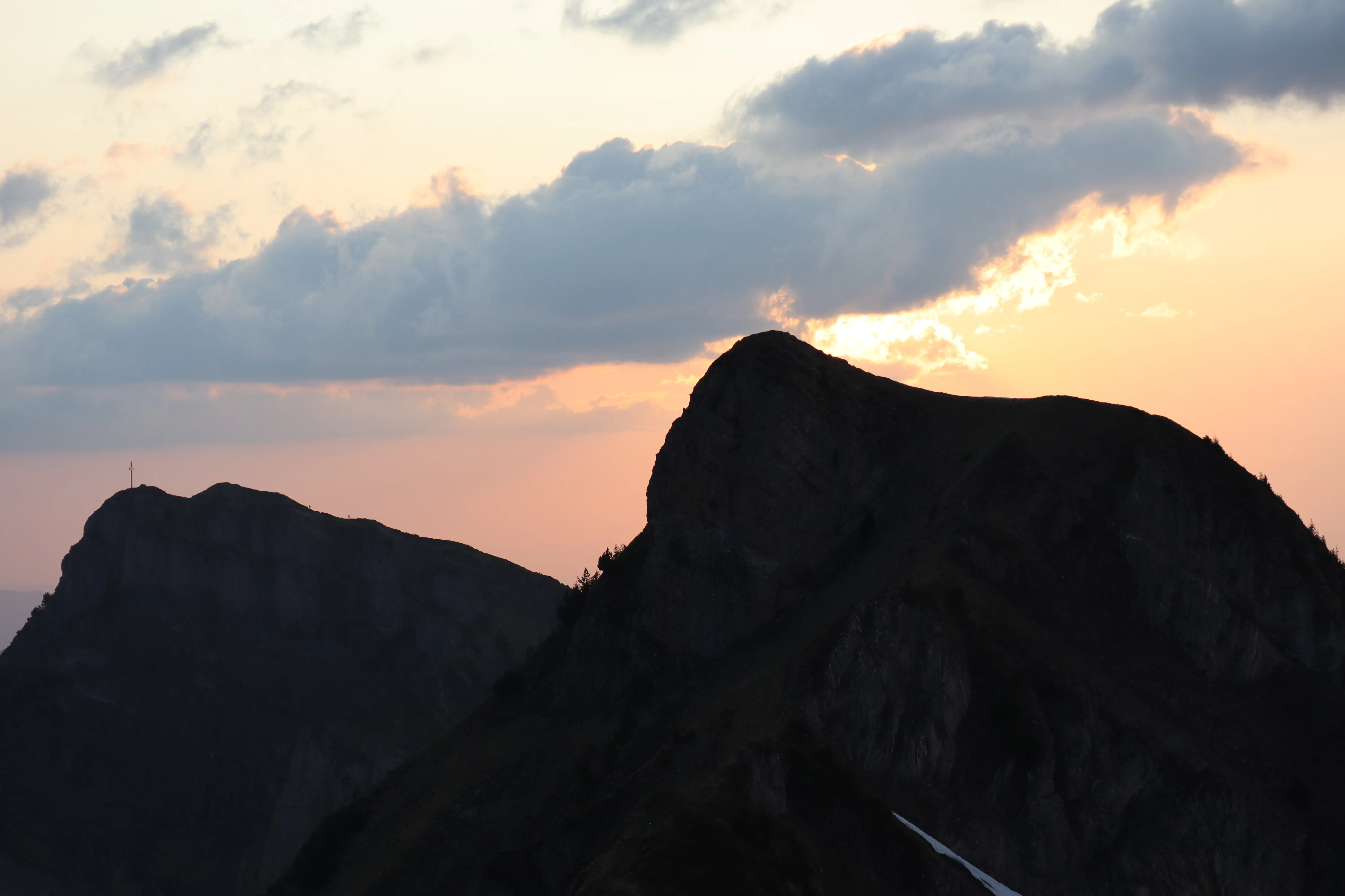 Pyramid-shaped peak silhouetted against a soft orange sunset sky.