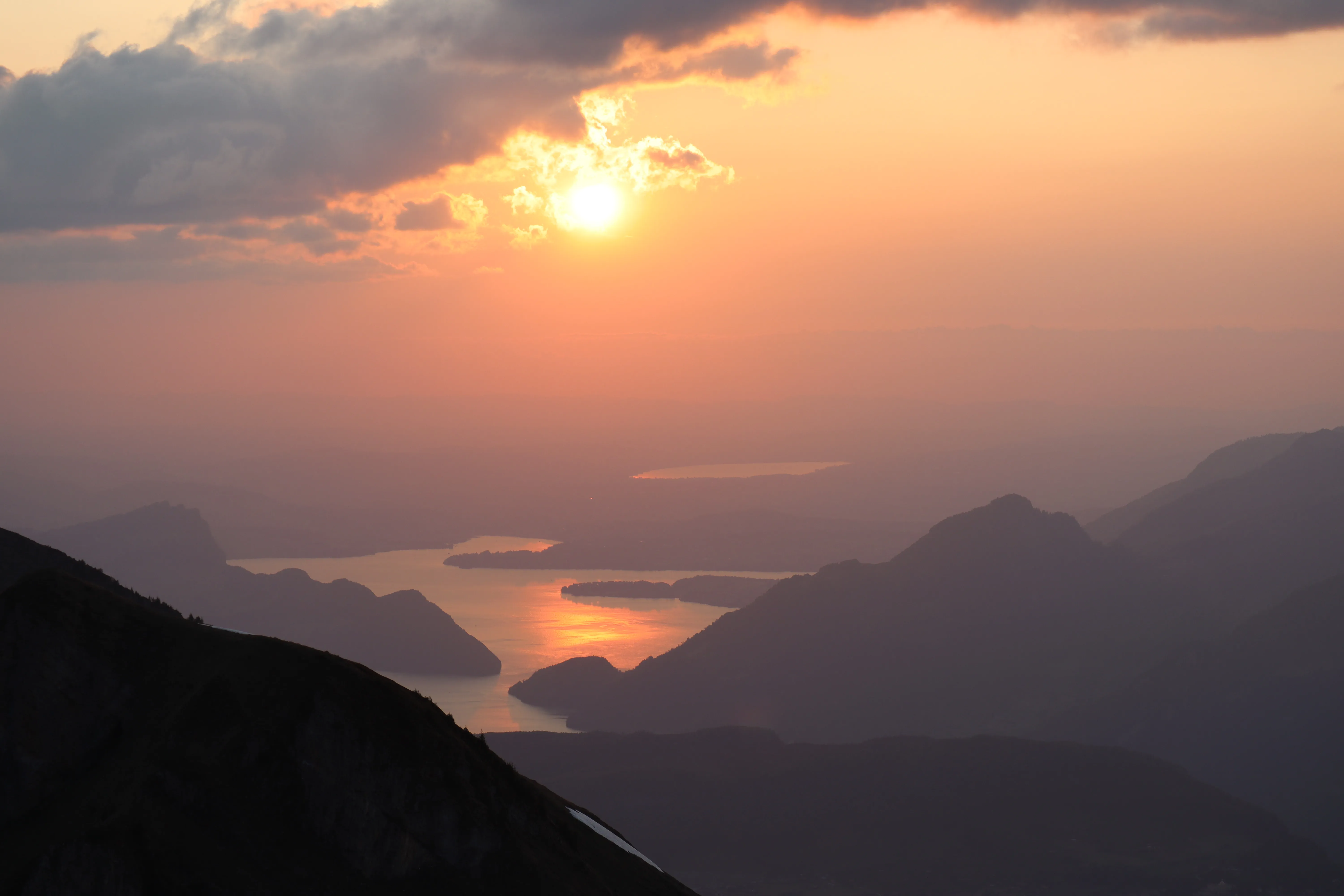 Sun setting over Lake Lucerne, the water glowing copper between dark ridges.