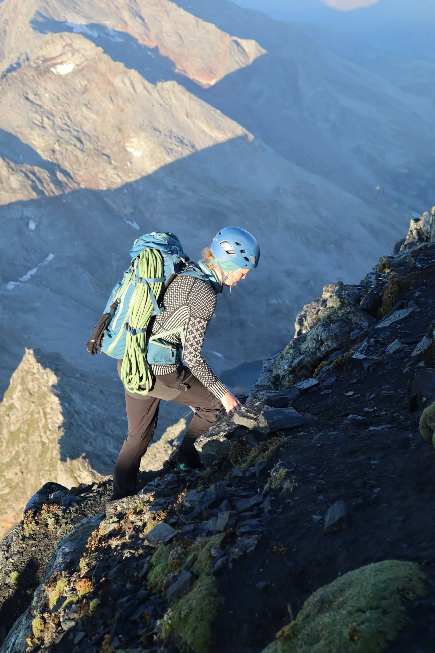 Climber moving over exposed rock high above the valley.
