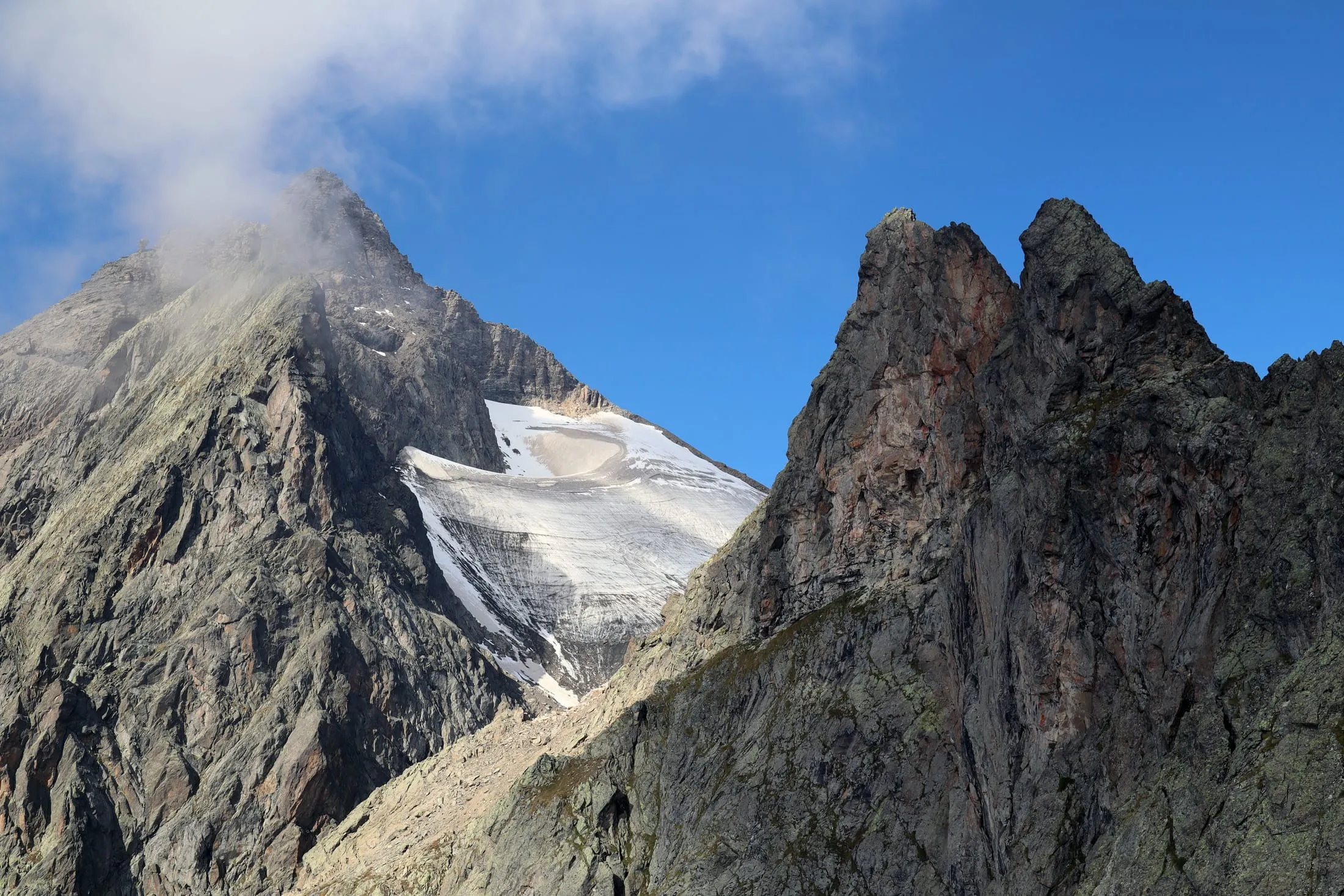 Climber in helmet and harness balancing on a narrow rocky ridge.