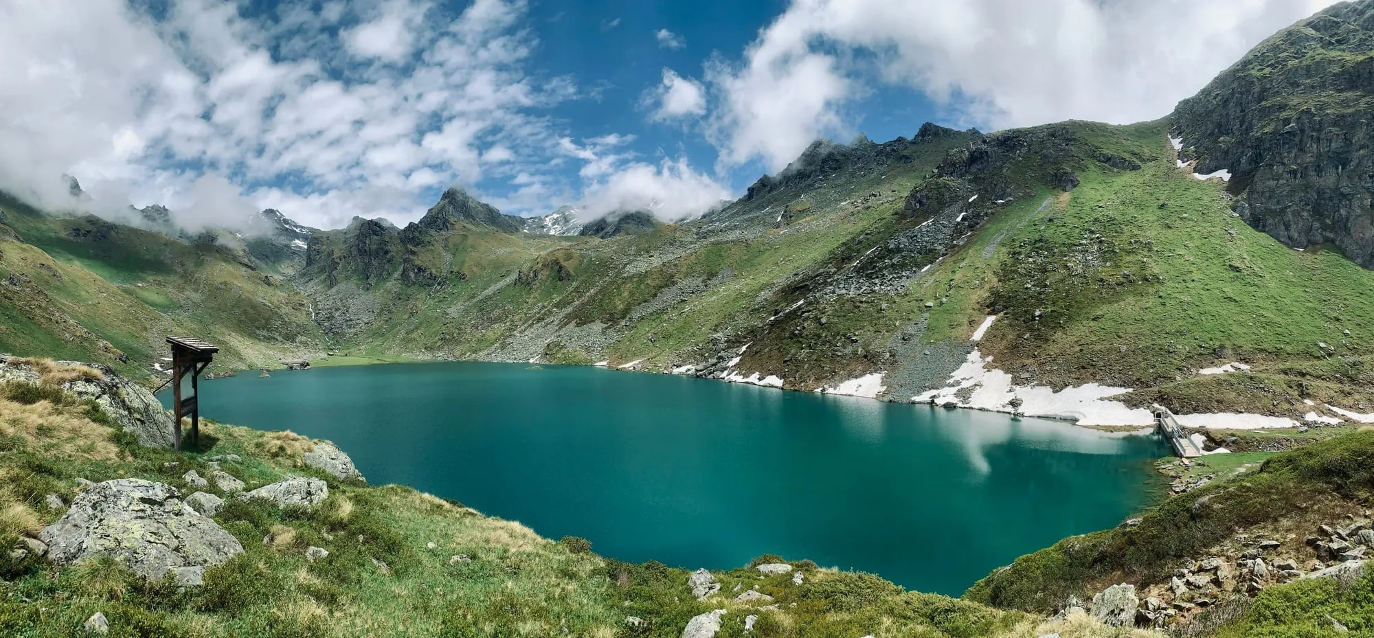 Lac de Louvie in a green summer basin below the Grand Combin, on the high traverse above Bagnes.