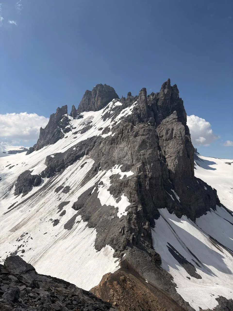 Las dentadas torres de roca del Gross Spannort alzándose sobre los neveros bajo un cielo azul.