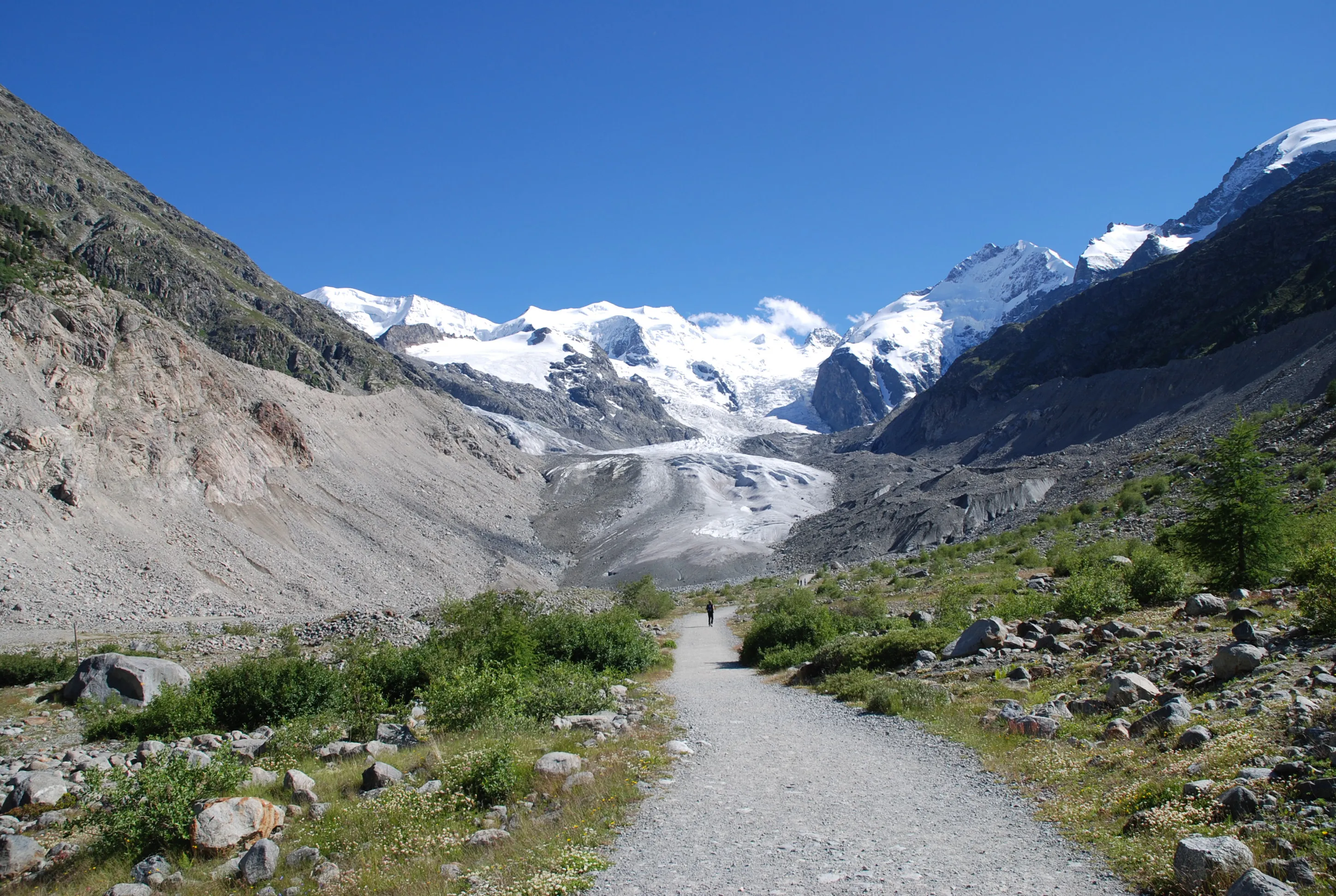 The Morteratsch glacier in summer, the trail leading to the glacier tongue with Piz Palü, Bellavista and Piz Bernina behind.