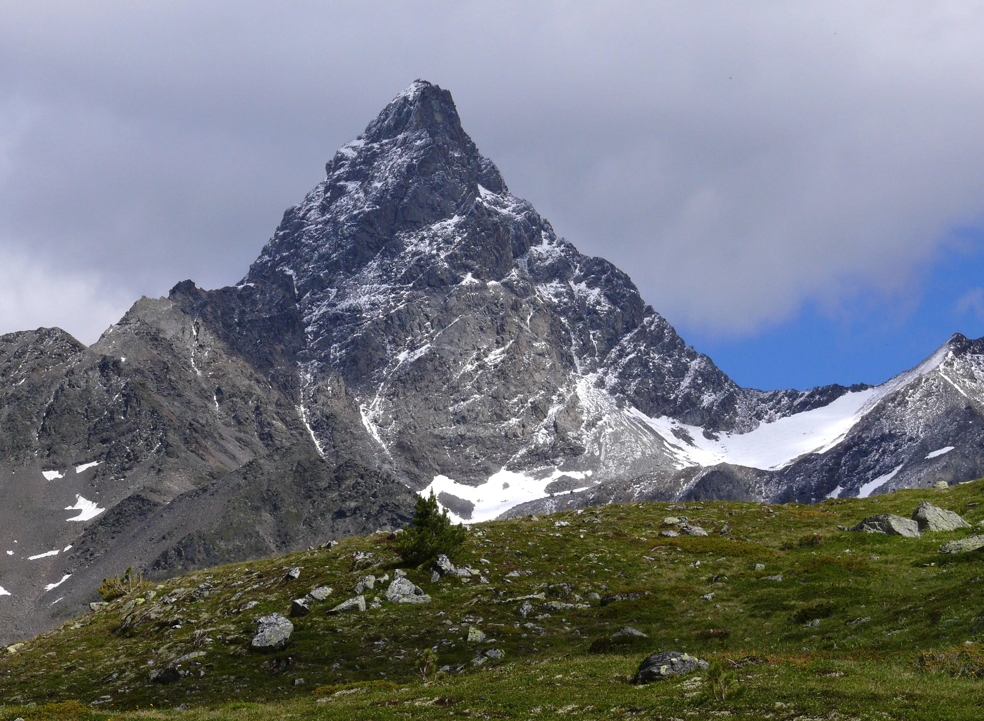 Piz Kesch (3418 m) in the Albula Alps, its striking pyramid rising above alpine pastures.