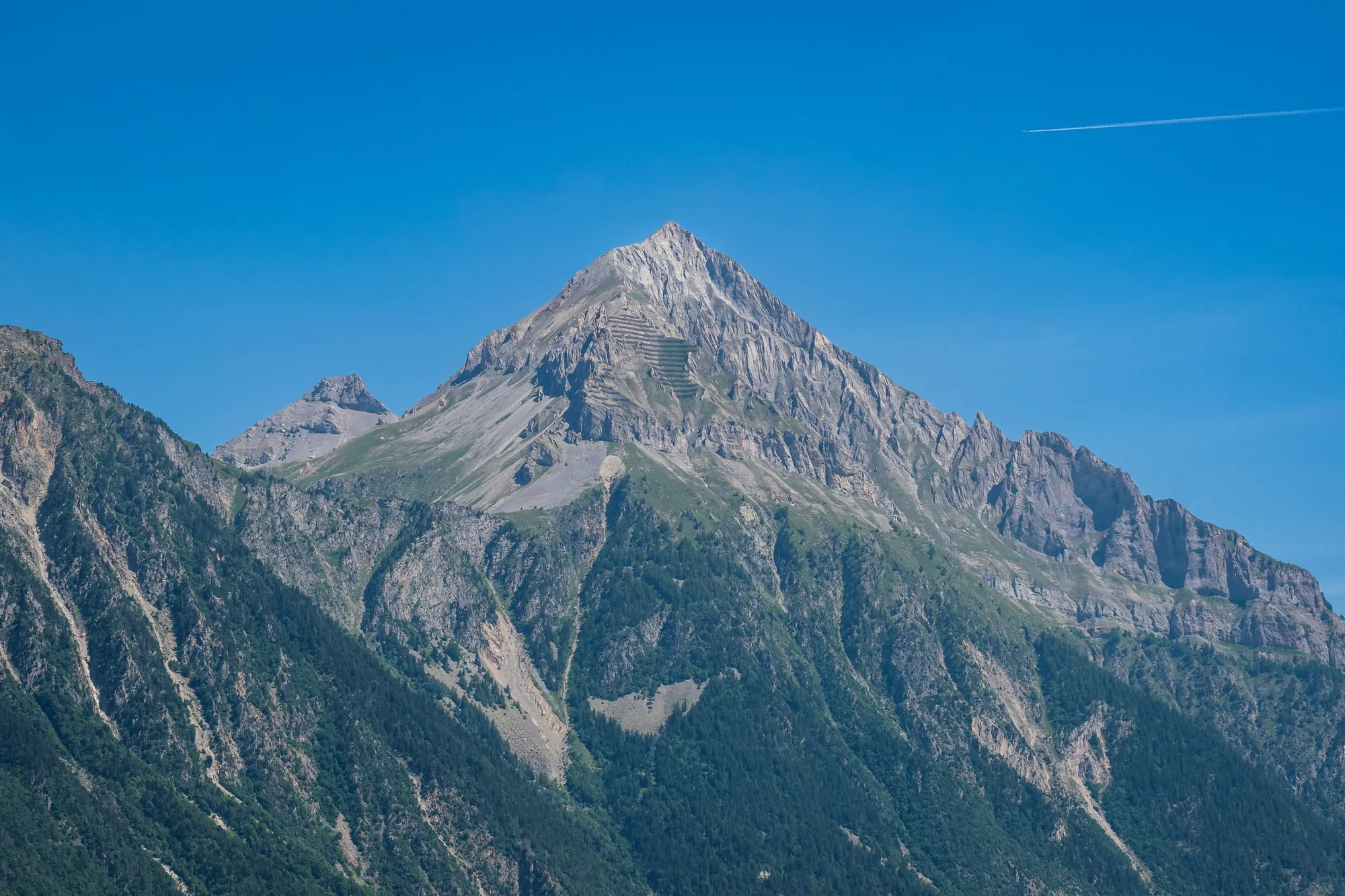 The rocky pyramid of the Grand Chavalard rising over green summer pastures above Ovronnaz.