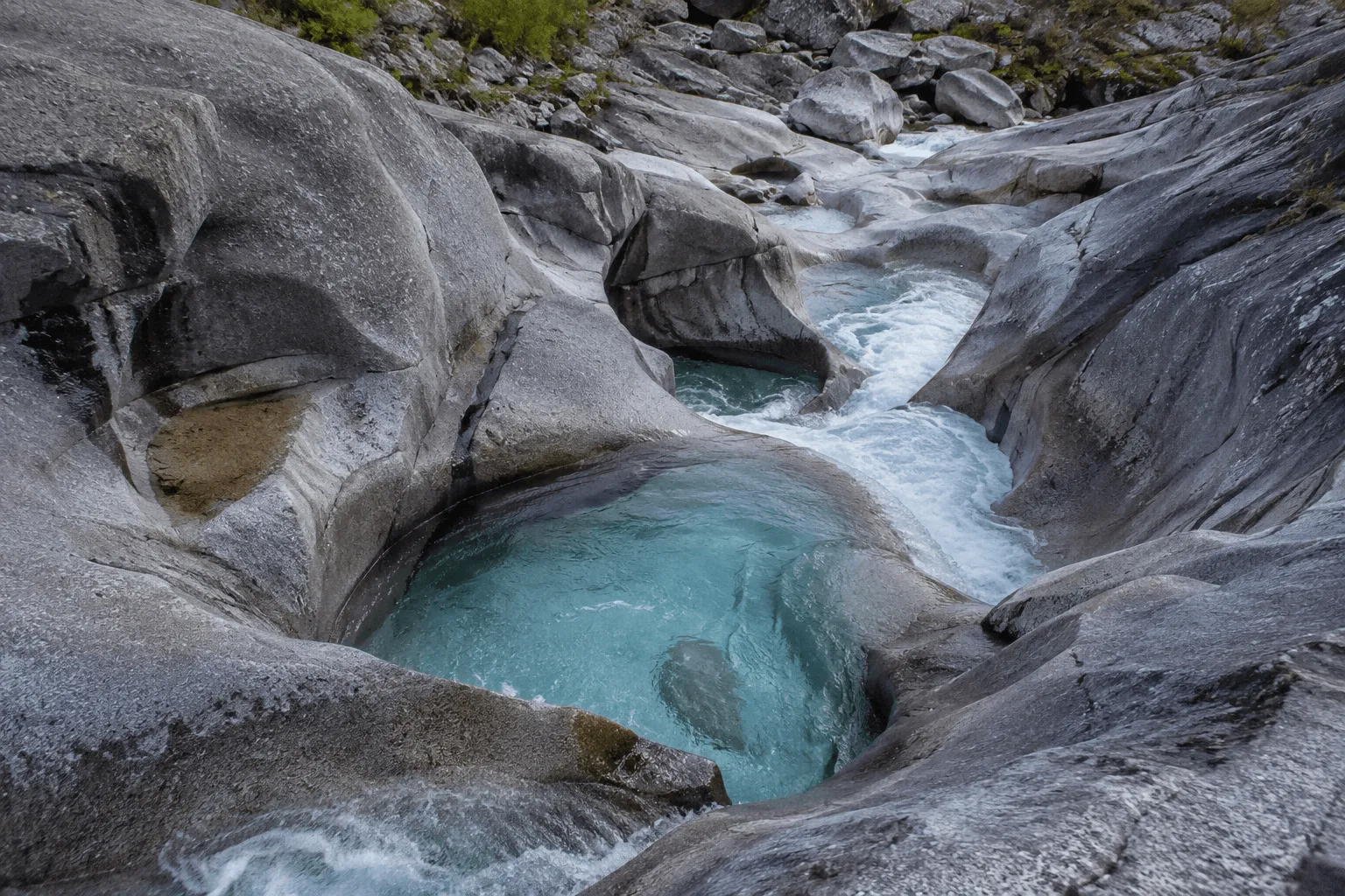 Water-scoured potholes in a mountain stream — smooth, round basins carved into the bedrock.