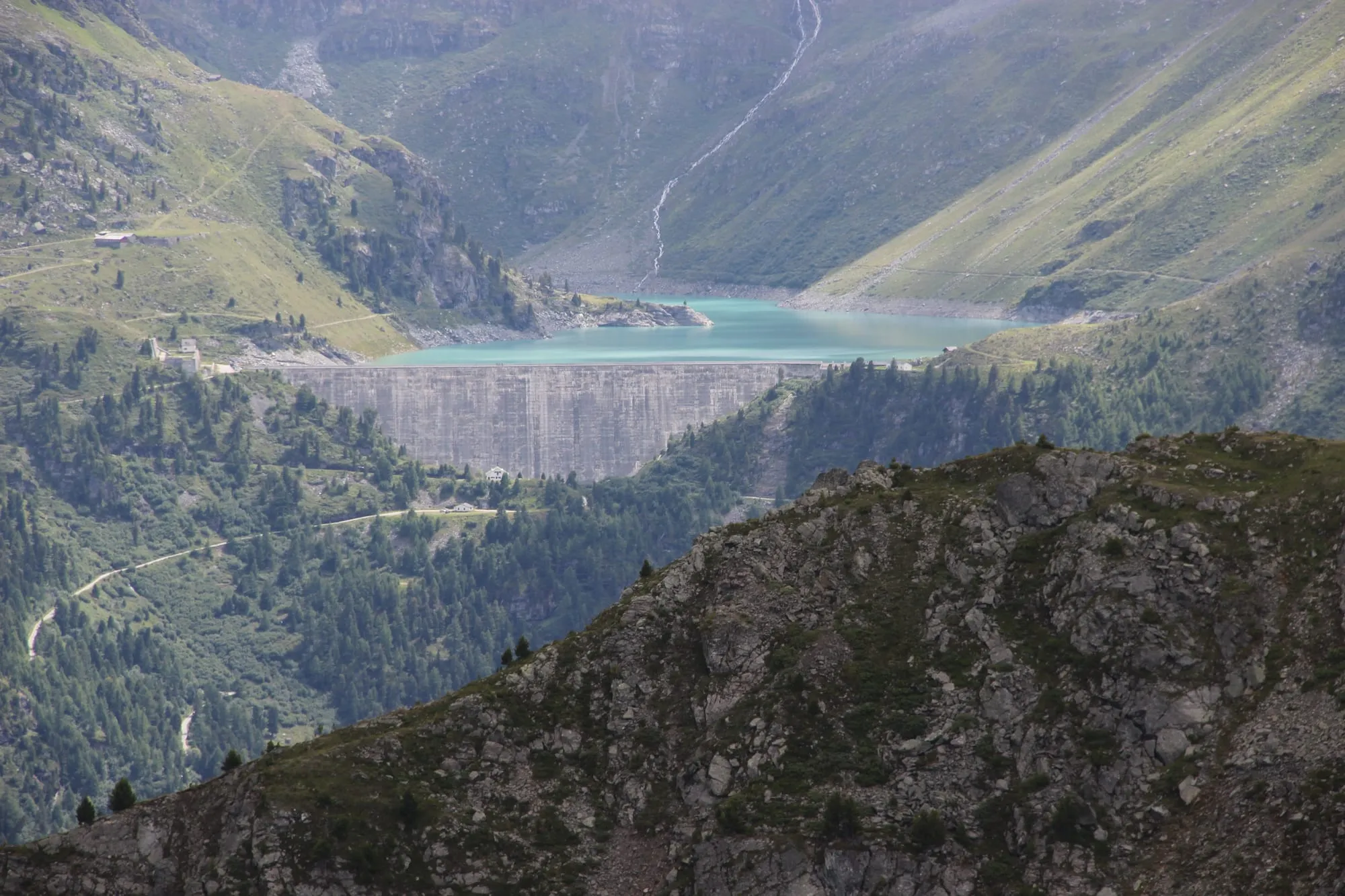The Lac de Cleuson reservoir behind its curved dam wall above Nendaz in summer.