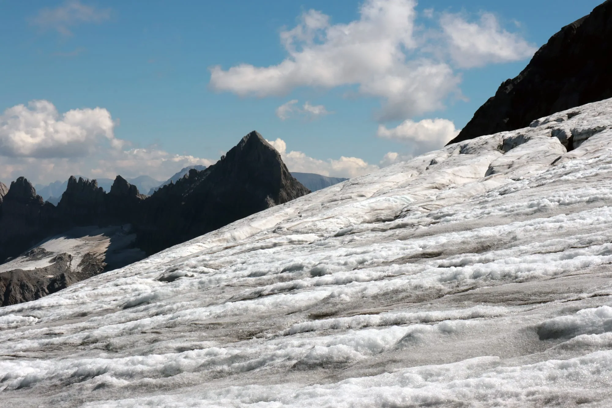 The bare glacier runs diagonally across the frame, a dark rock spire to the left under building clouds.