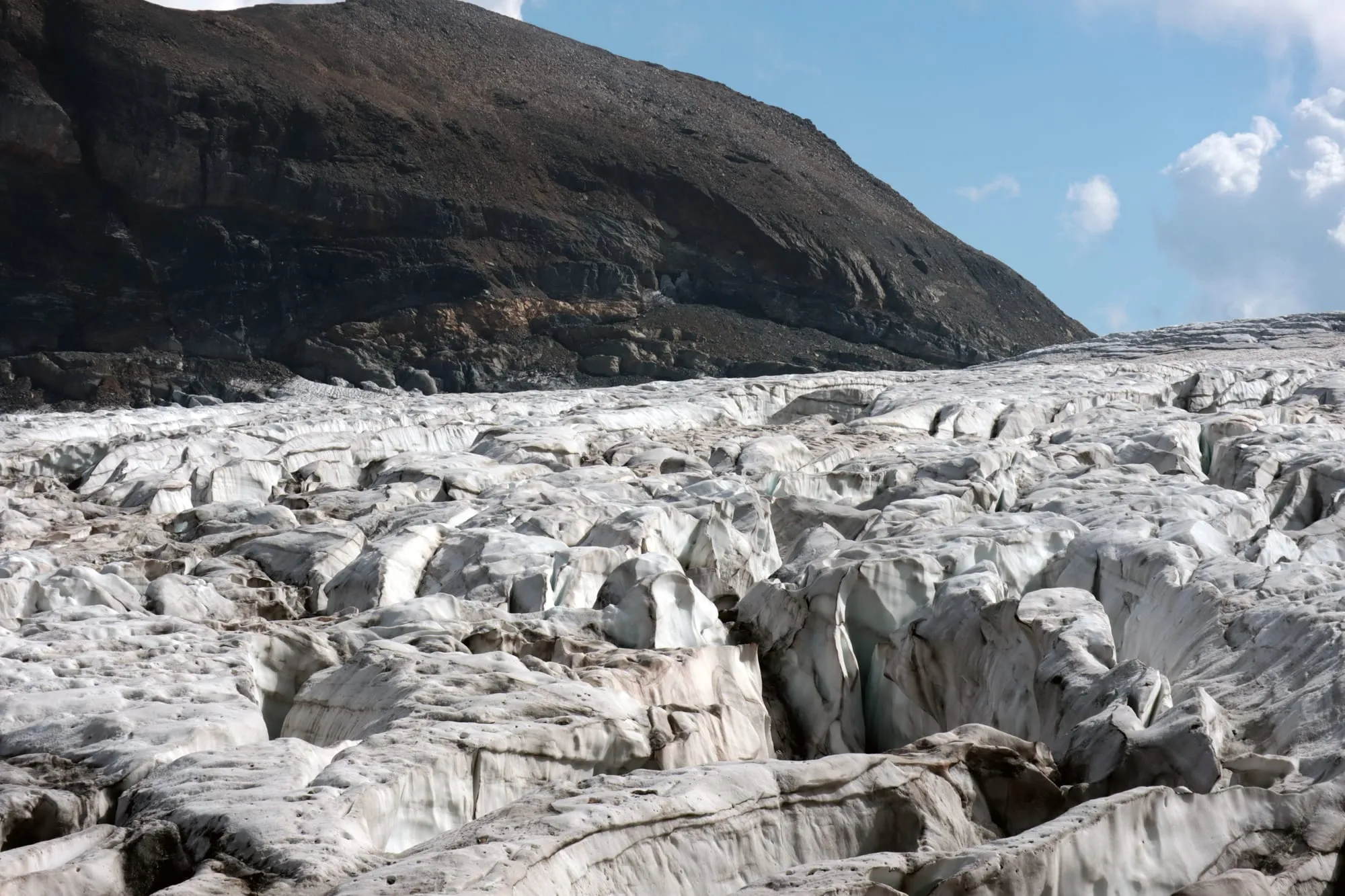 The broken icefall below a dark, layered rock wall.