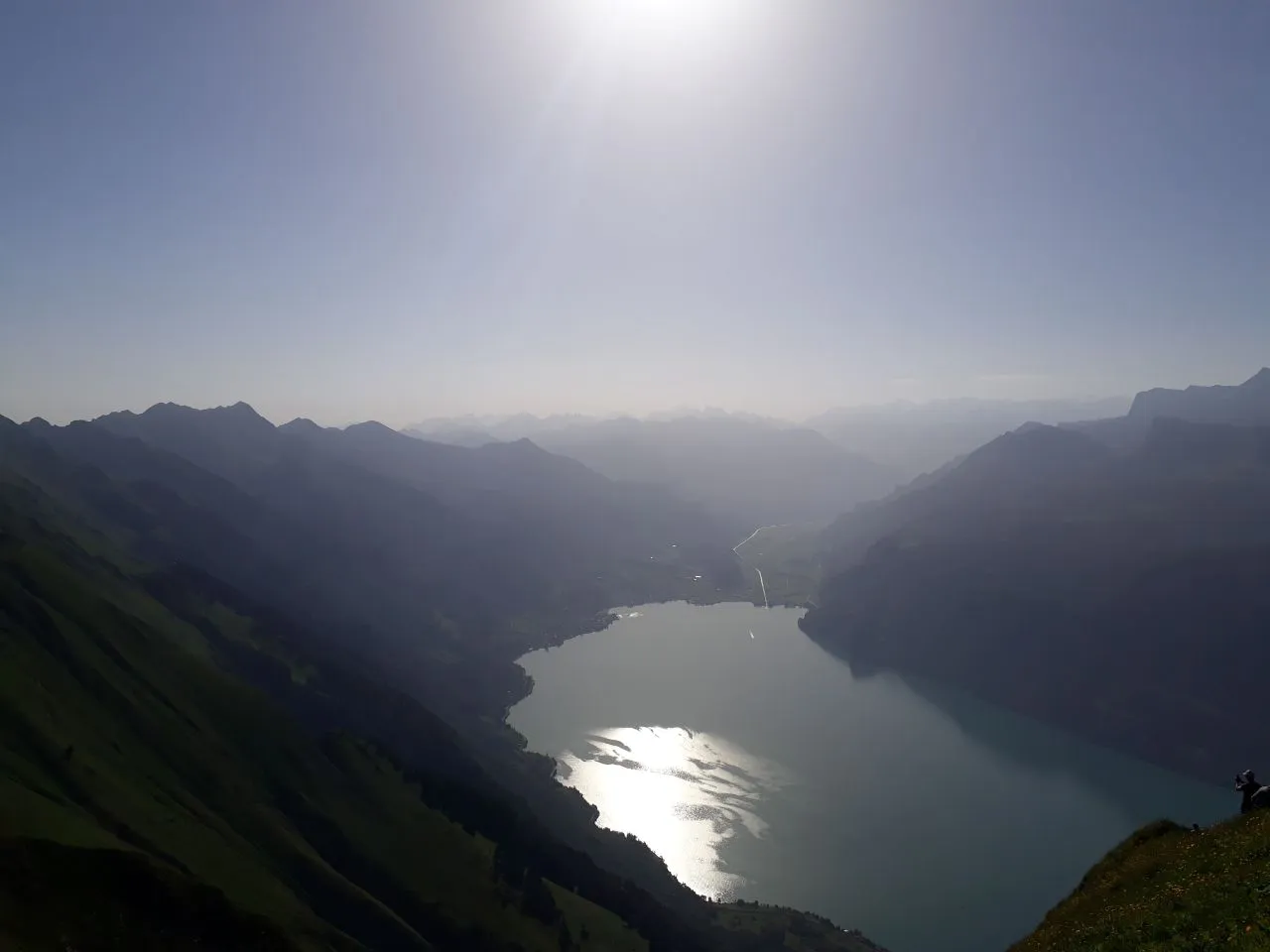 Looking steeply down from the ridge to Lake Brienz, the low sun glinting silver off the water between hazy ranges.