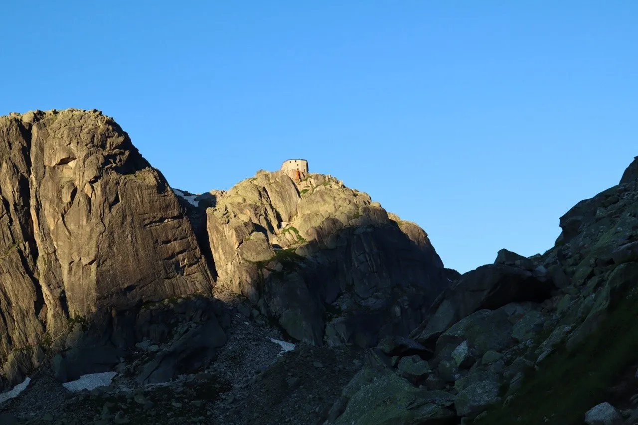 Evening light on a granite summit, crowned by an old stone fortification.