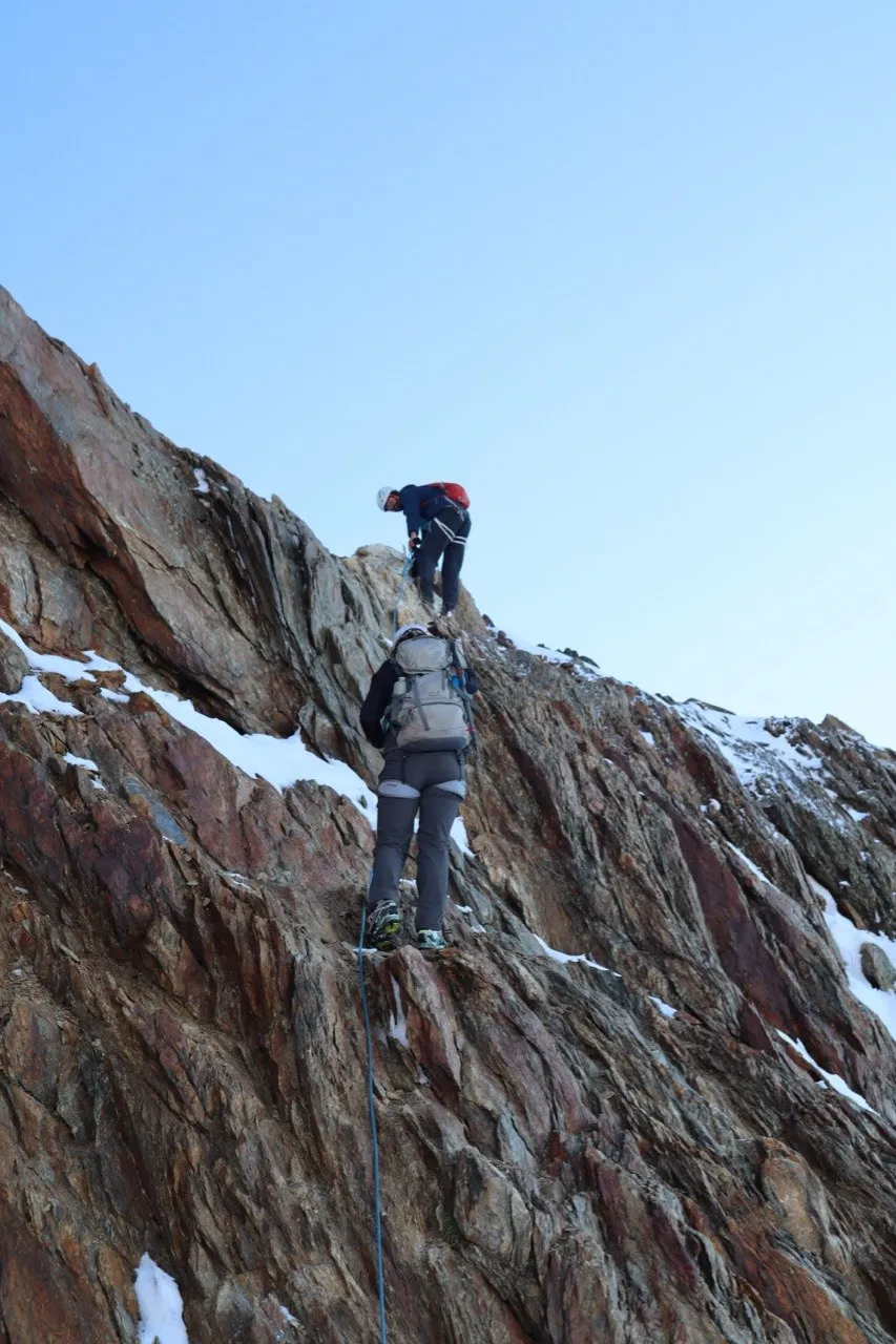 Climber scrambling up a steep rock step on the rope.