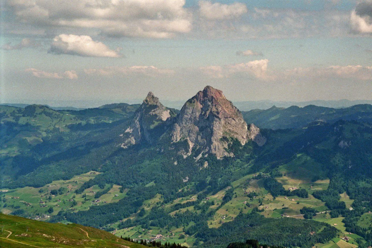 The Grosser and Kleiner Mythen stand as a striking pair of rock peaks above a green pre-alpine valley dotted with farms.