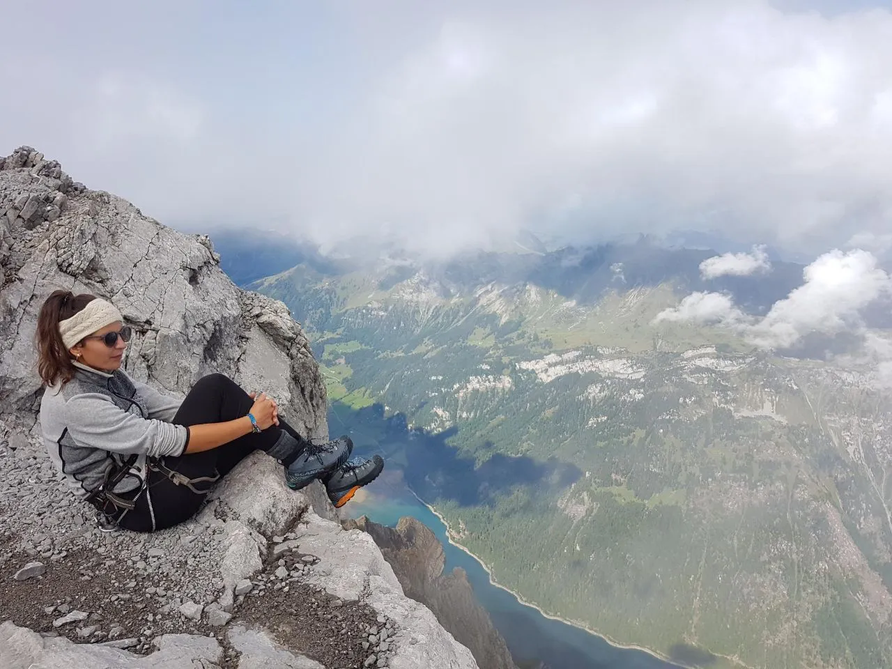 Mountaineer resting on a rocky ledge on the Glärnisch, the Klöntalersee far below.