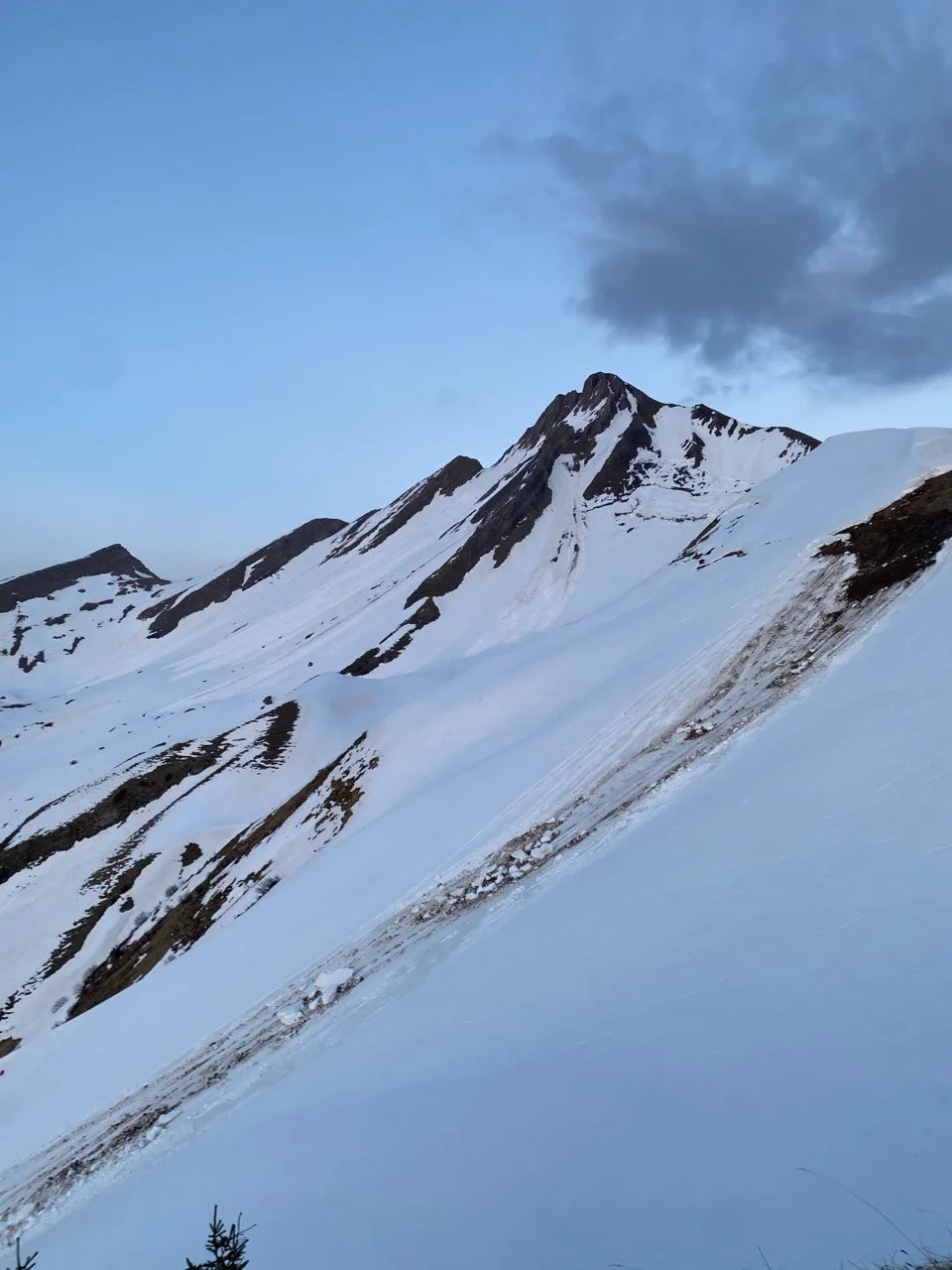 A snow-covered peak beneath gathering dark clouds at dusk.
