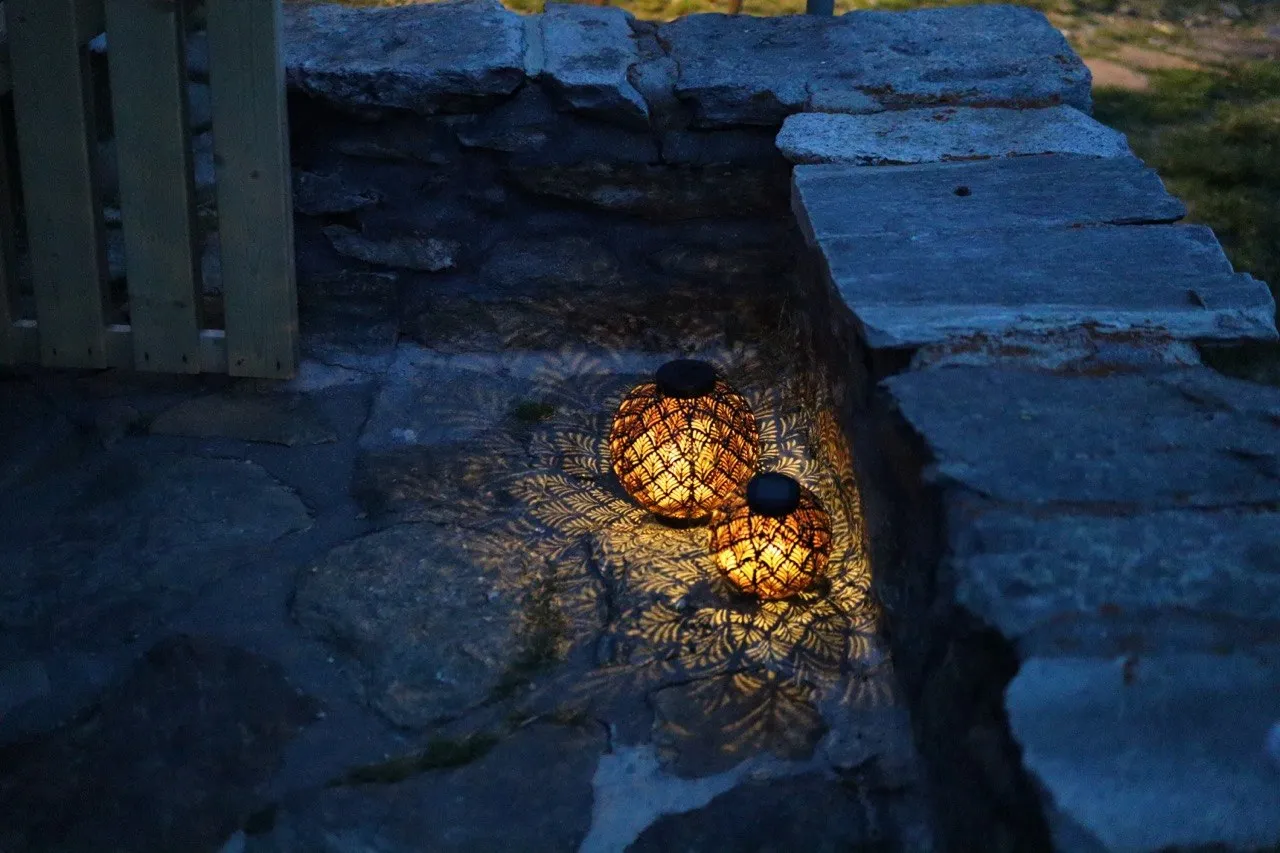 Two glowing lanterns cast shadows on a stone staircase at dusk.