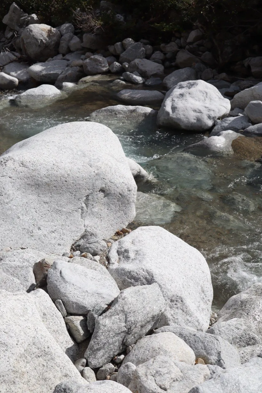 Smooth white boulders line a clear mountain stream.