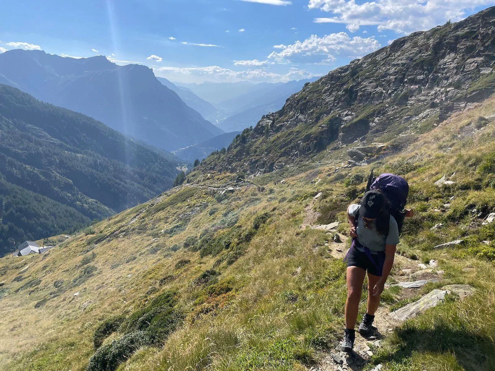 Hiker with a big pack on the approach trail above a deep valley.